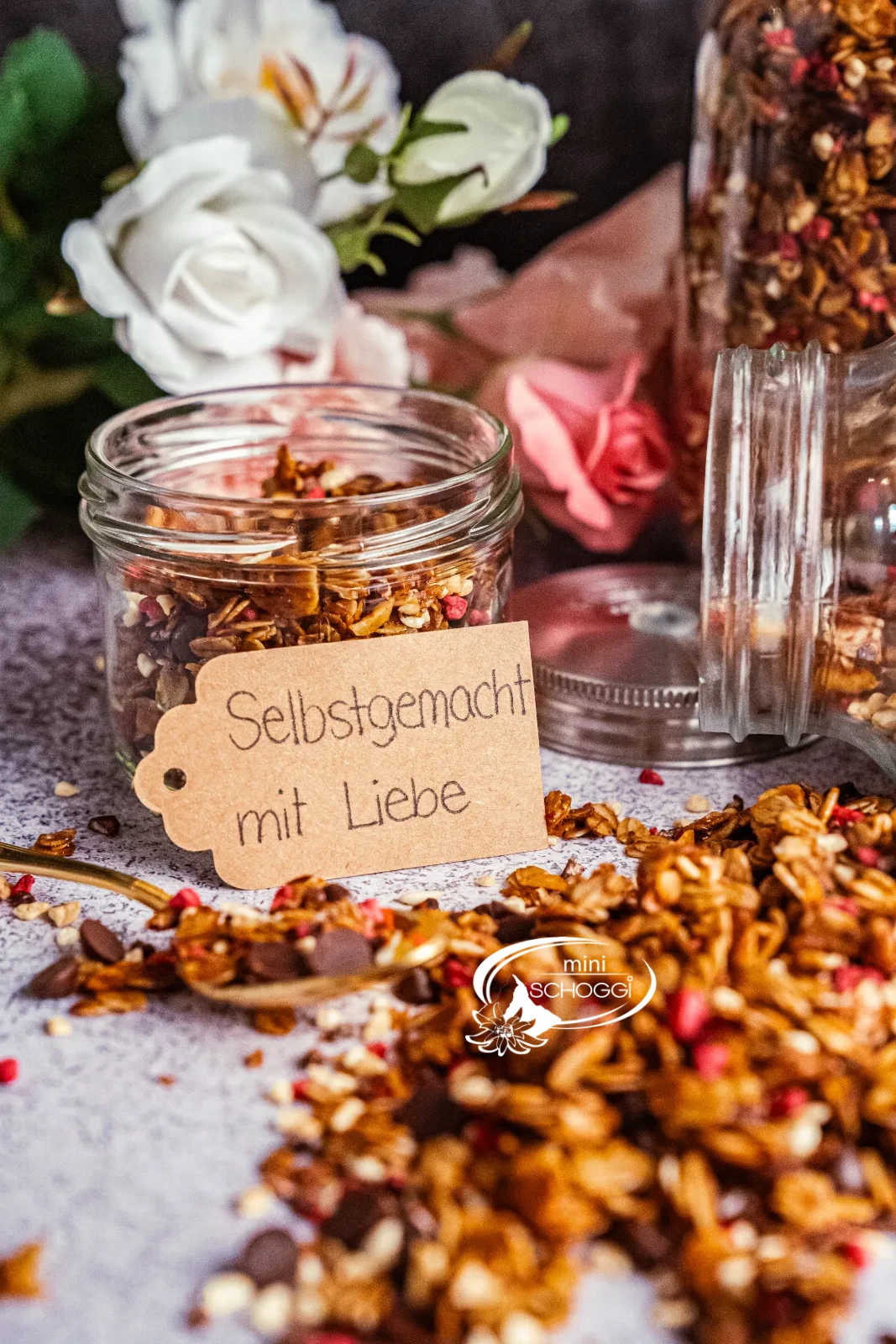 Granola fatta in casa con lamponi e cioccolato, accanto due vasetti di scorta