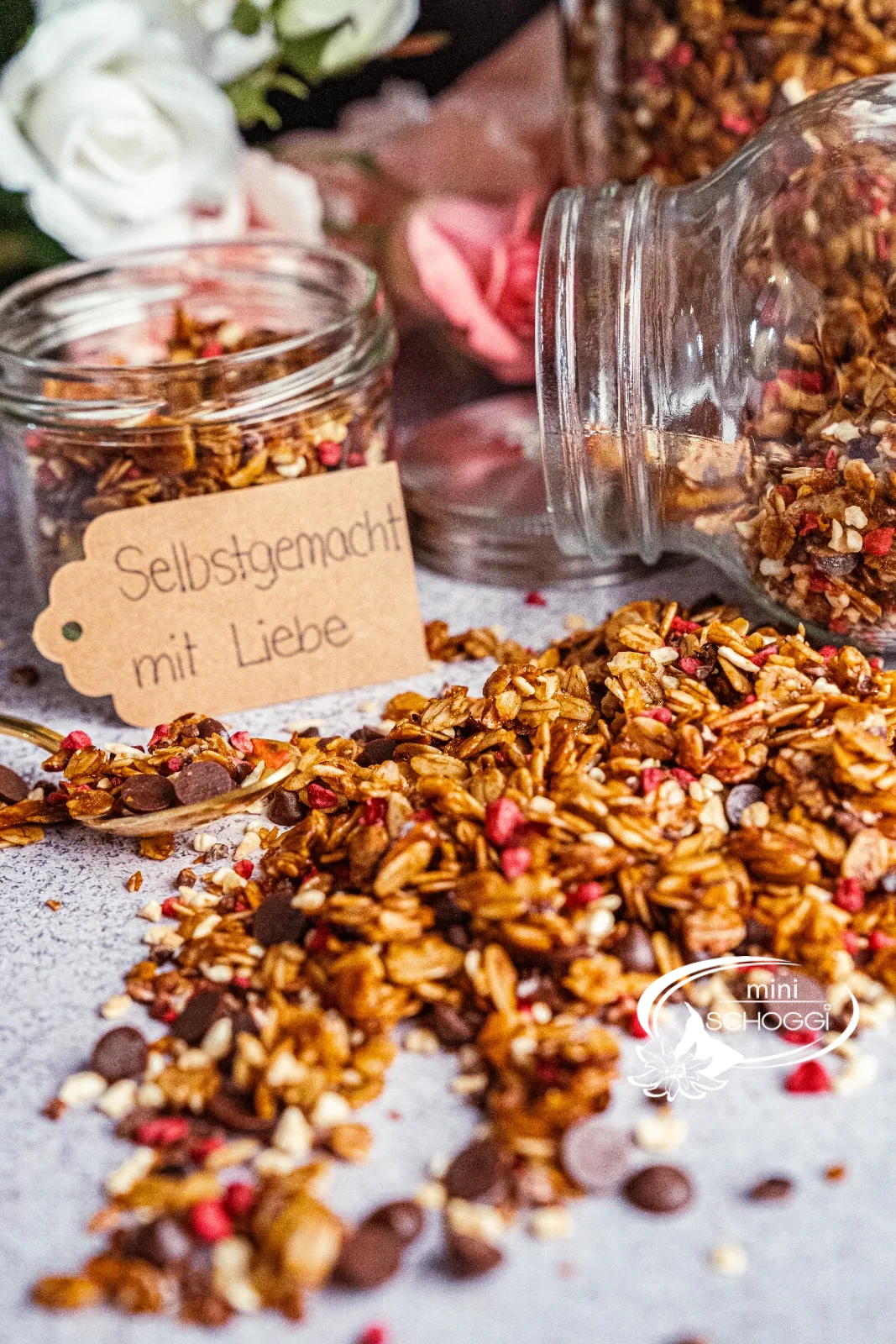 Granola pronta con Gocce di cioccolato e lamponi accanto a due vasetti