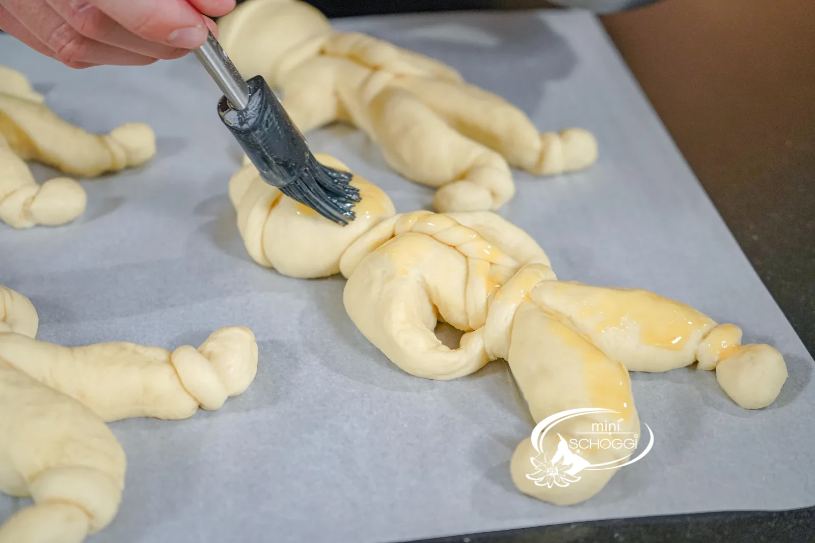 L'omino di pasta lievitata viene spennellato uniformemente con l'uovo usando il pennello