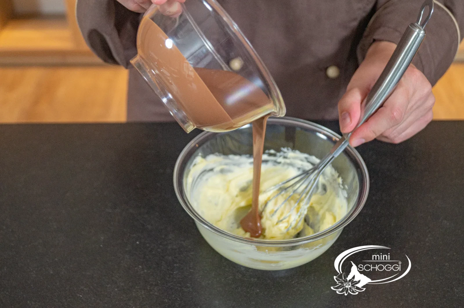Erste Portion temperierte Milchcouverture wird in die Butter-Fondantmasse gegossen