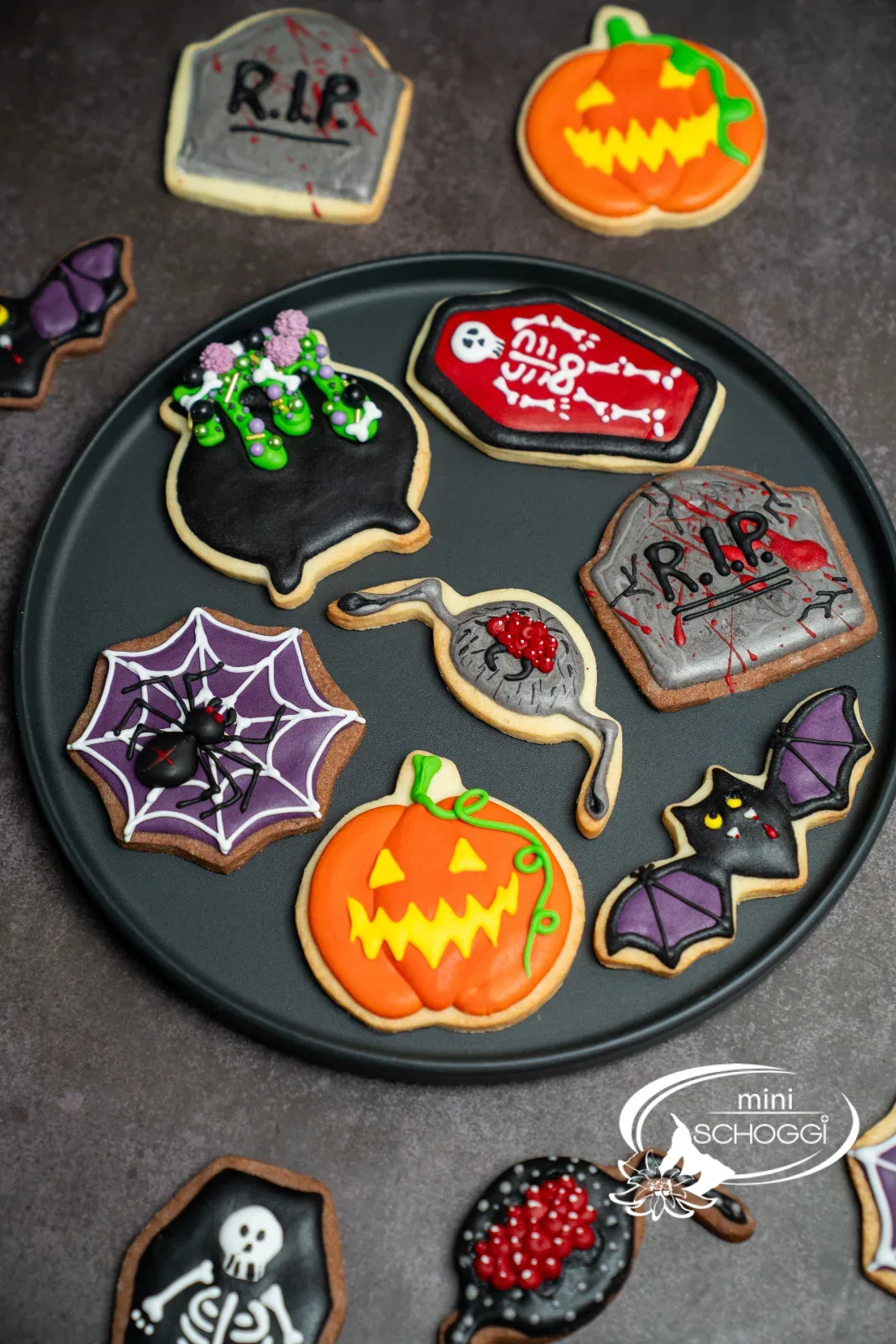 Verzierte Halloween-Guetzli auf einem dunklen Teller