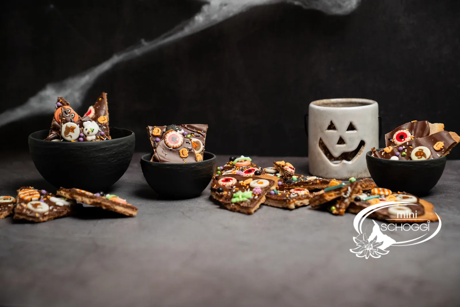 Halloween-Bruchschokolade mit Karamell, dunkler Couverture und Halloween-Deko auf einem weissen Teller