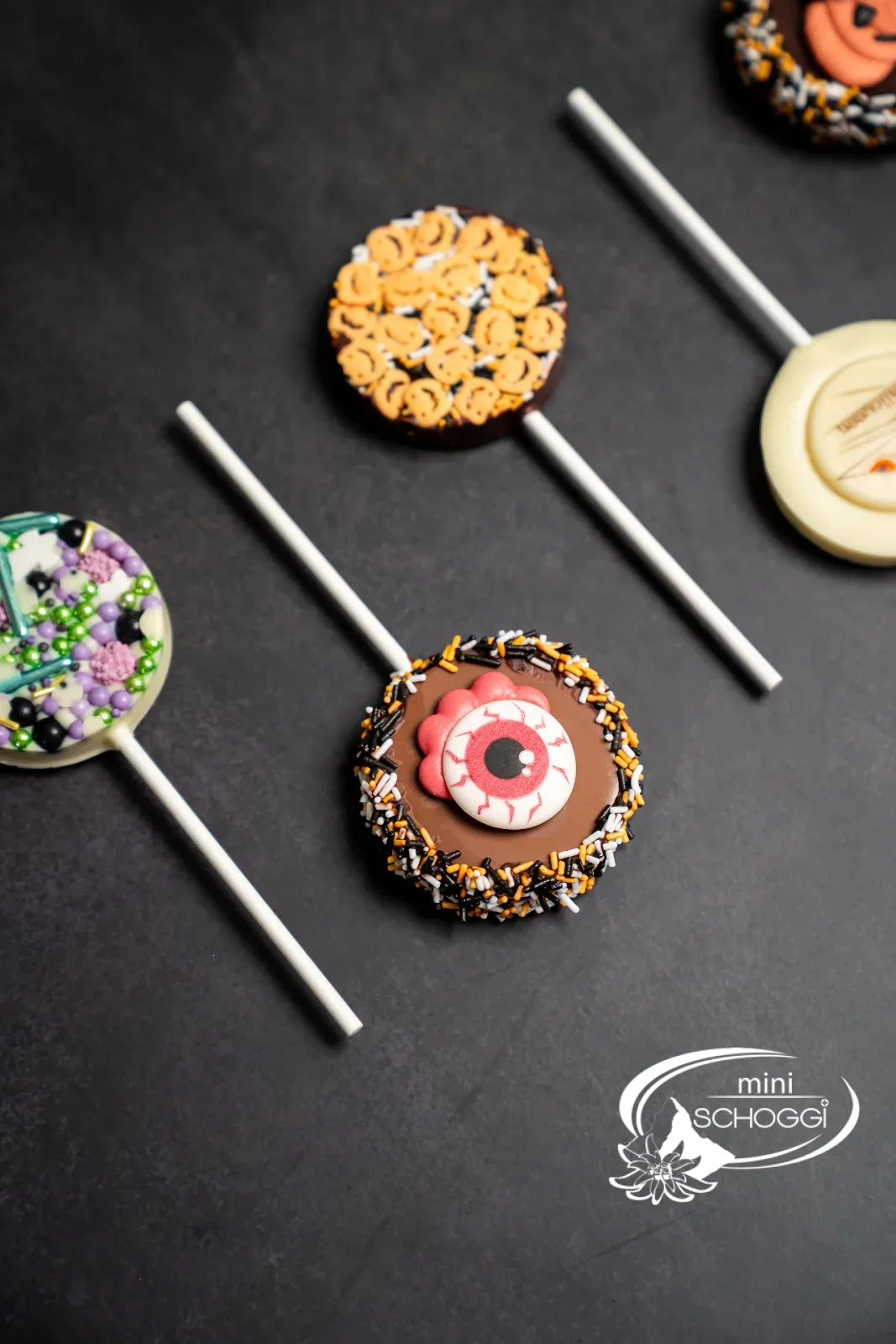 Verpackte Halloween-Lollipops mit Schleifen in Gläsern voller Streusel