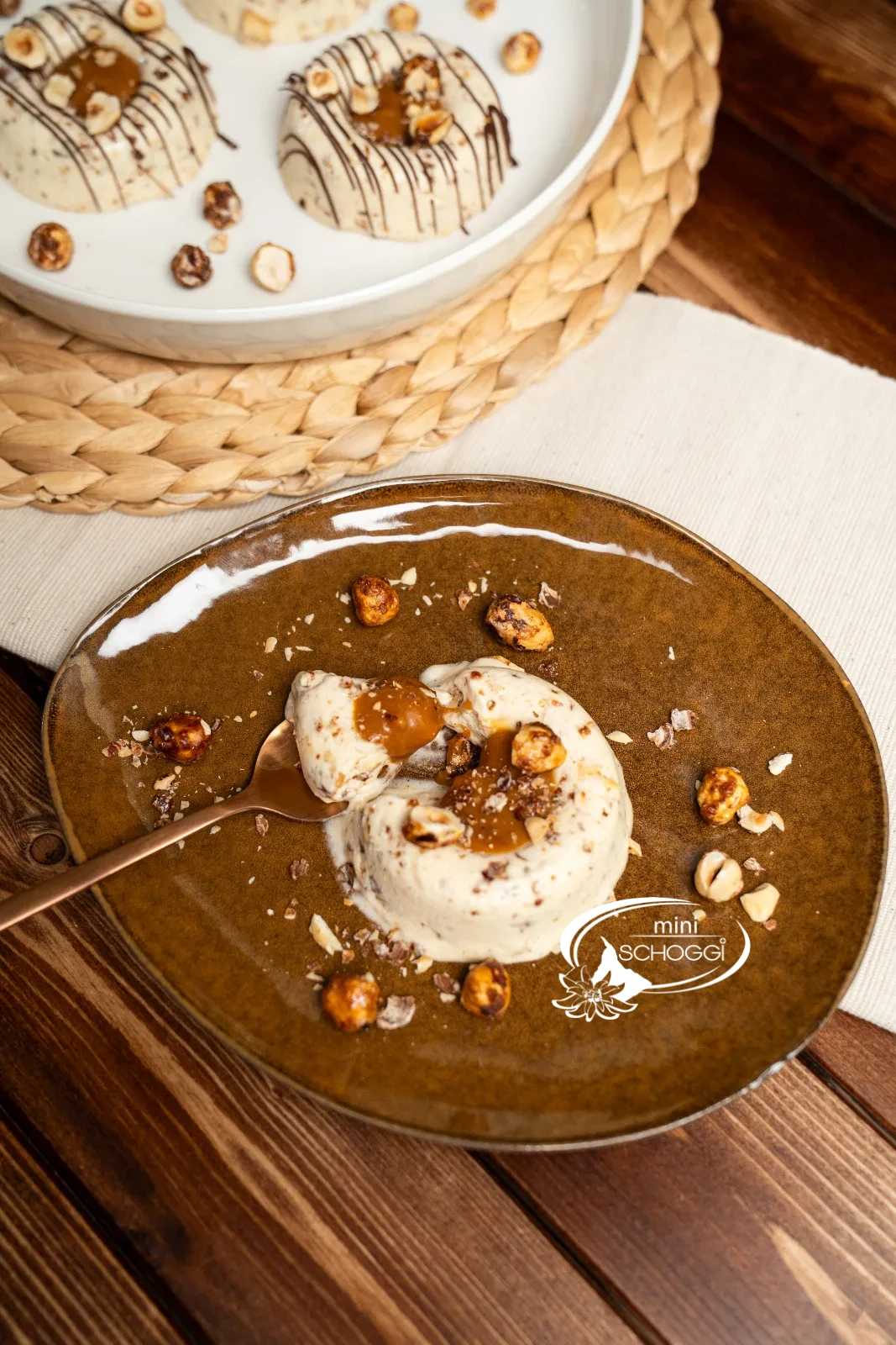 Zwei Teller mit Haselnuss-Karamell-Parfait, angerichtet mit Karamell und Nüssen