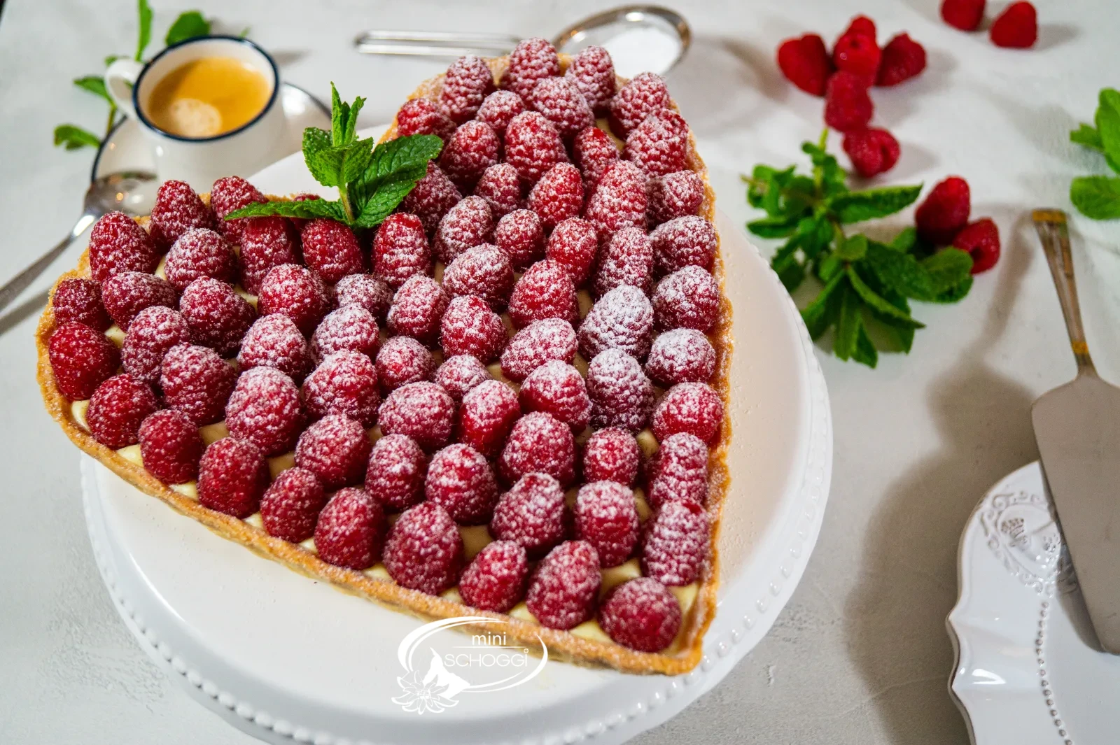 Herztorte mit Vanillecreme und frischen Himbeeren, mit Puderzucker bestäubt