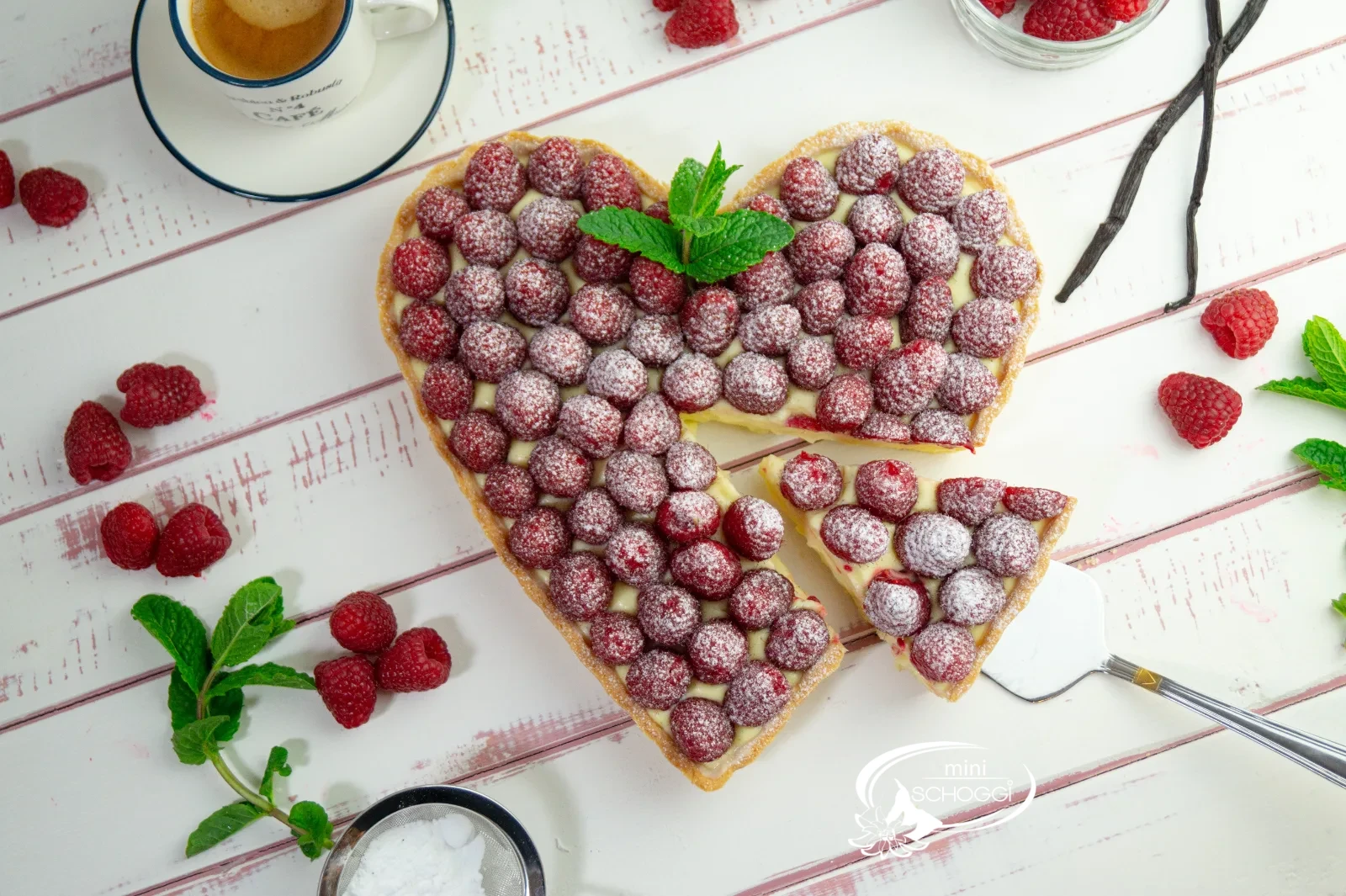 Herztorte mit Vanillecreme und frischen Himbeeren, mit Puderzucker bestäubt