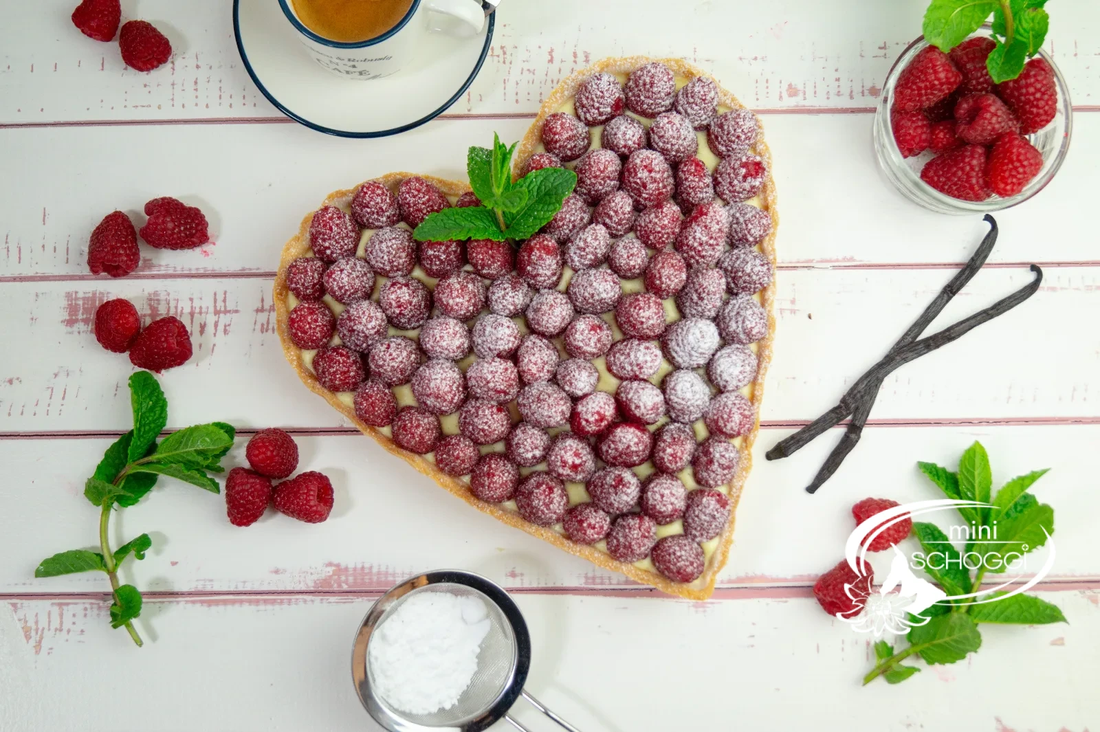 Herztorte mit Vanillecreme und frischen Himbeeren, mit Puderzucker bestäubt