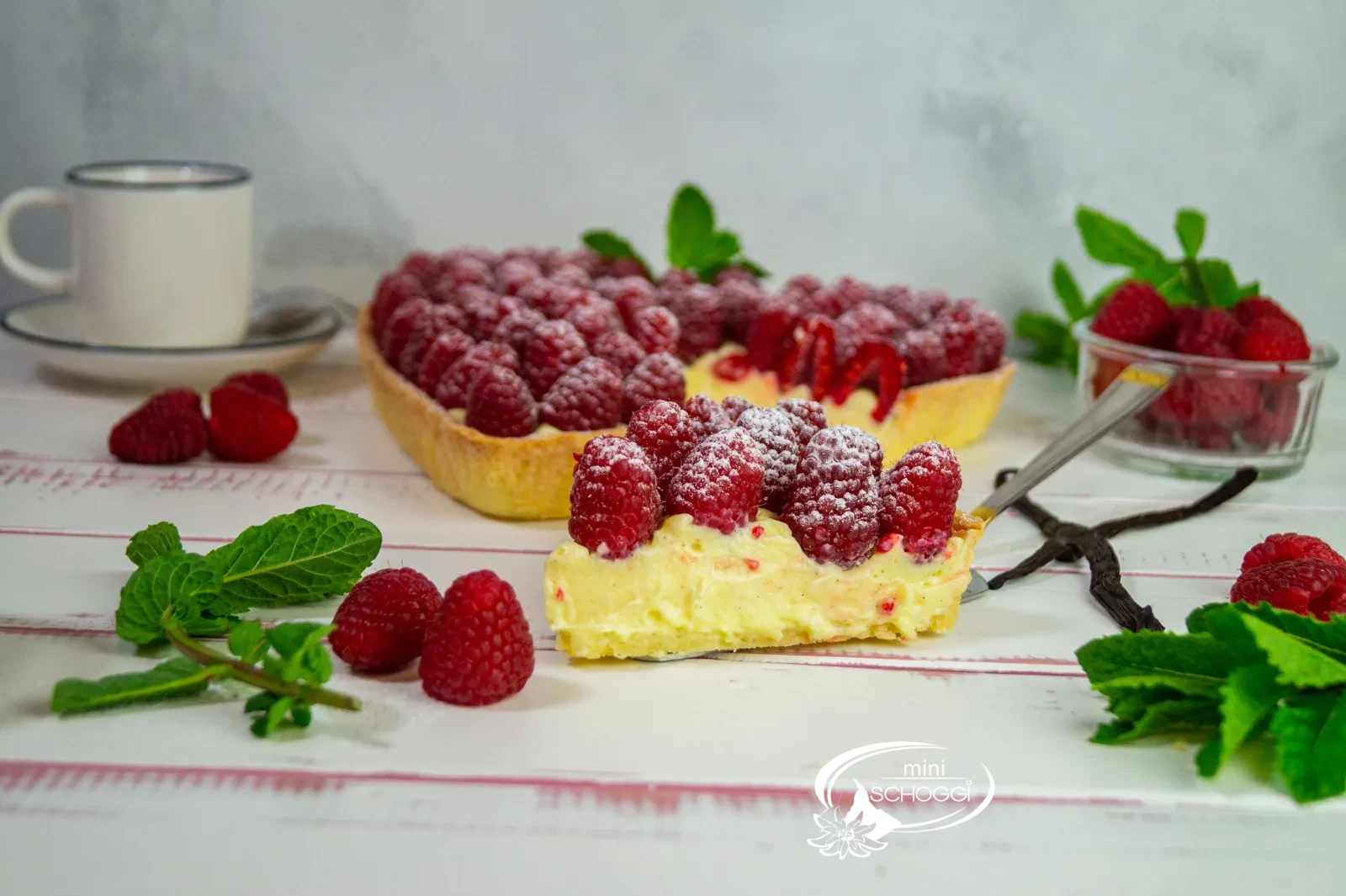 Herztorte mit Vanillecreme und frischen Himbeeren, mit Puderzucker bestäubt