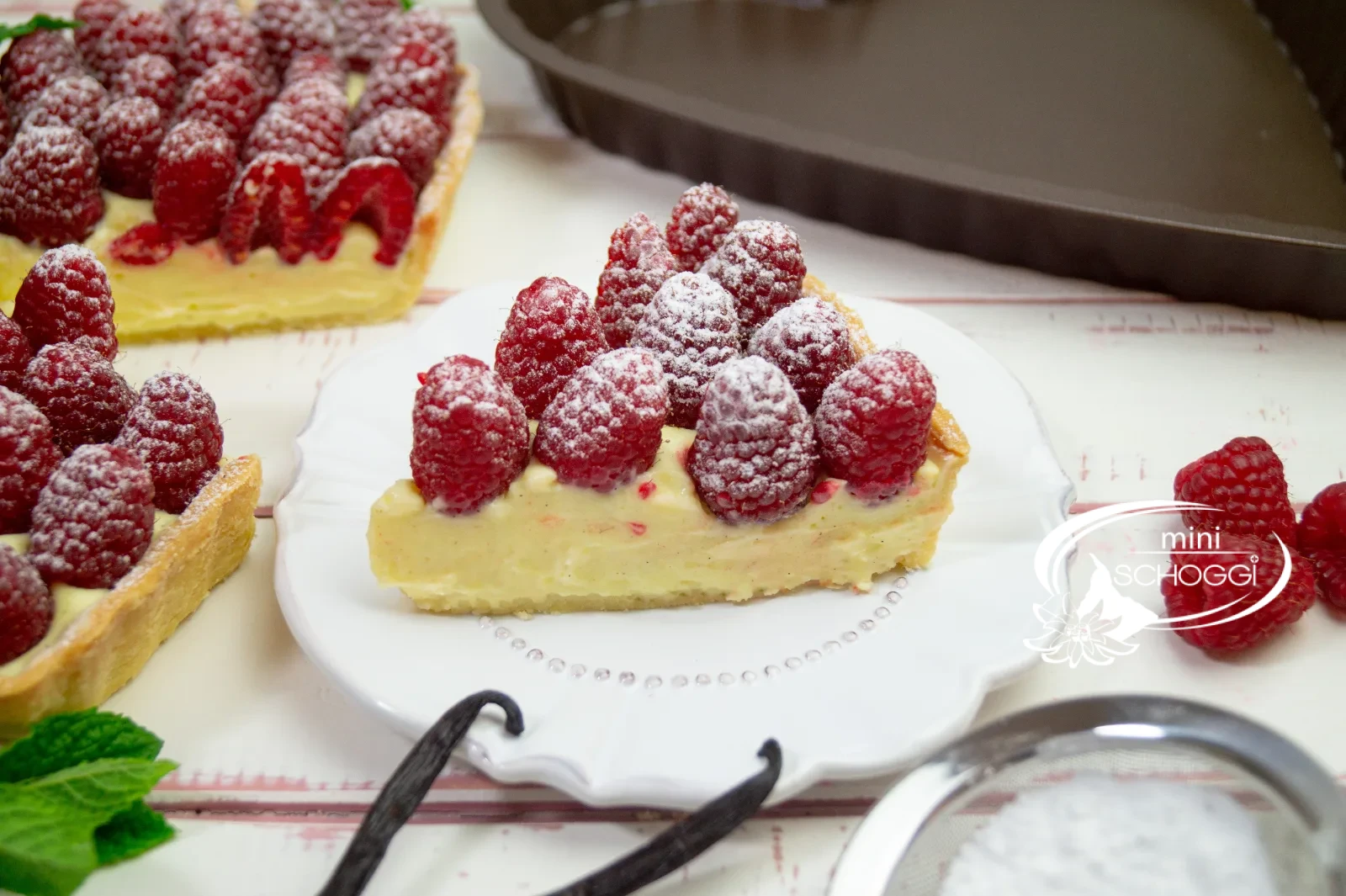 Herztorte mit Vanillecreme und frischen Himbeeren, mit Puderzucker bestäubt