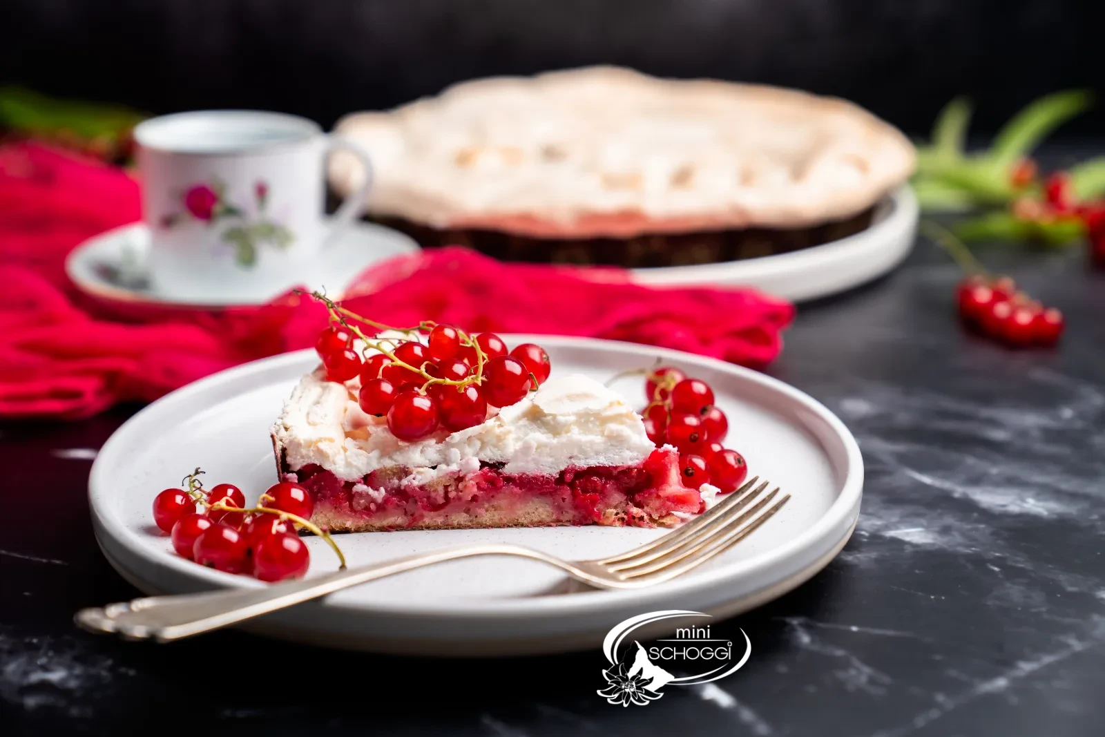 Fetta di torta con strati di base, ribes e meringa su un piatto bianco