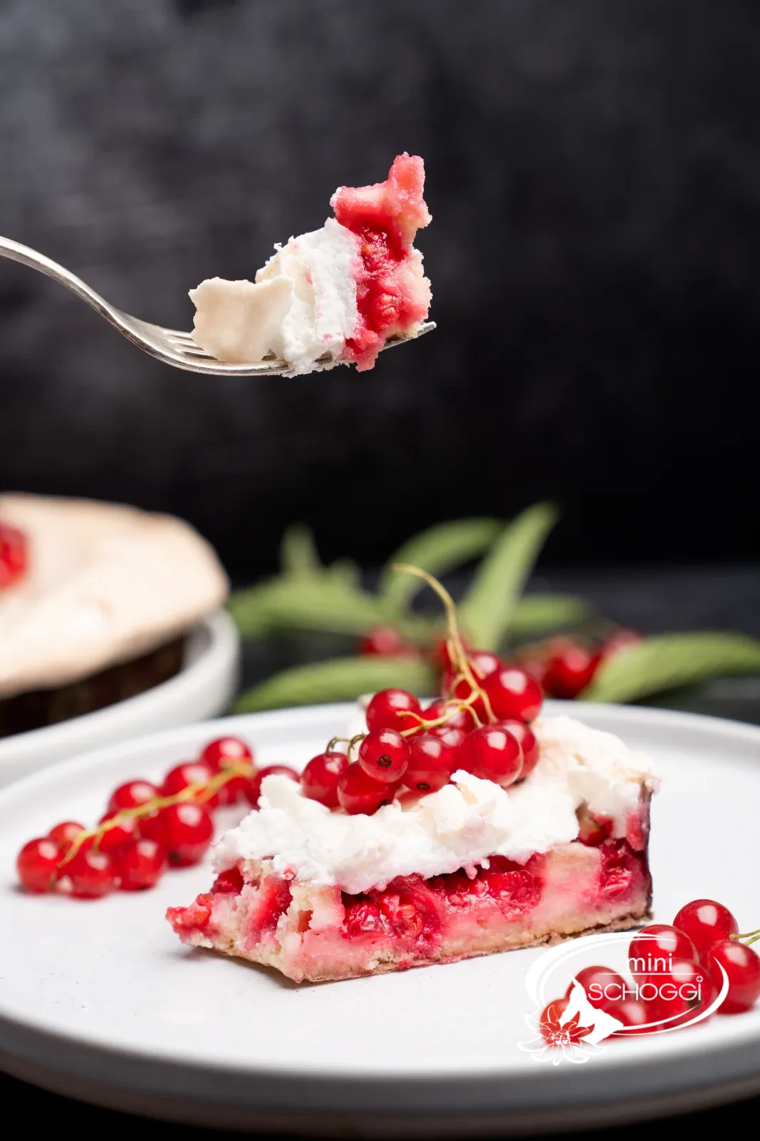 Fetta di torta con strati di base, ribes e meringa su un piatto bianco