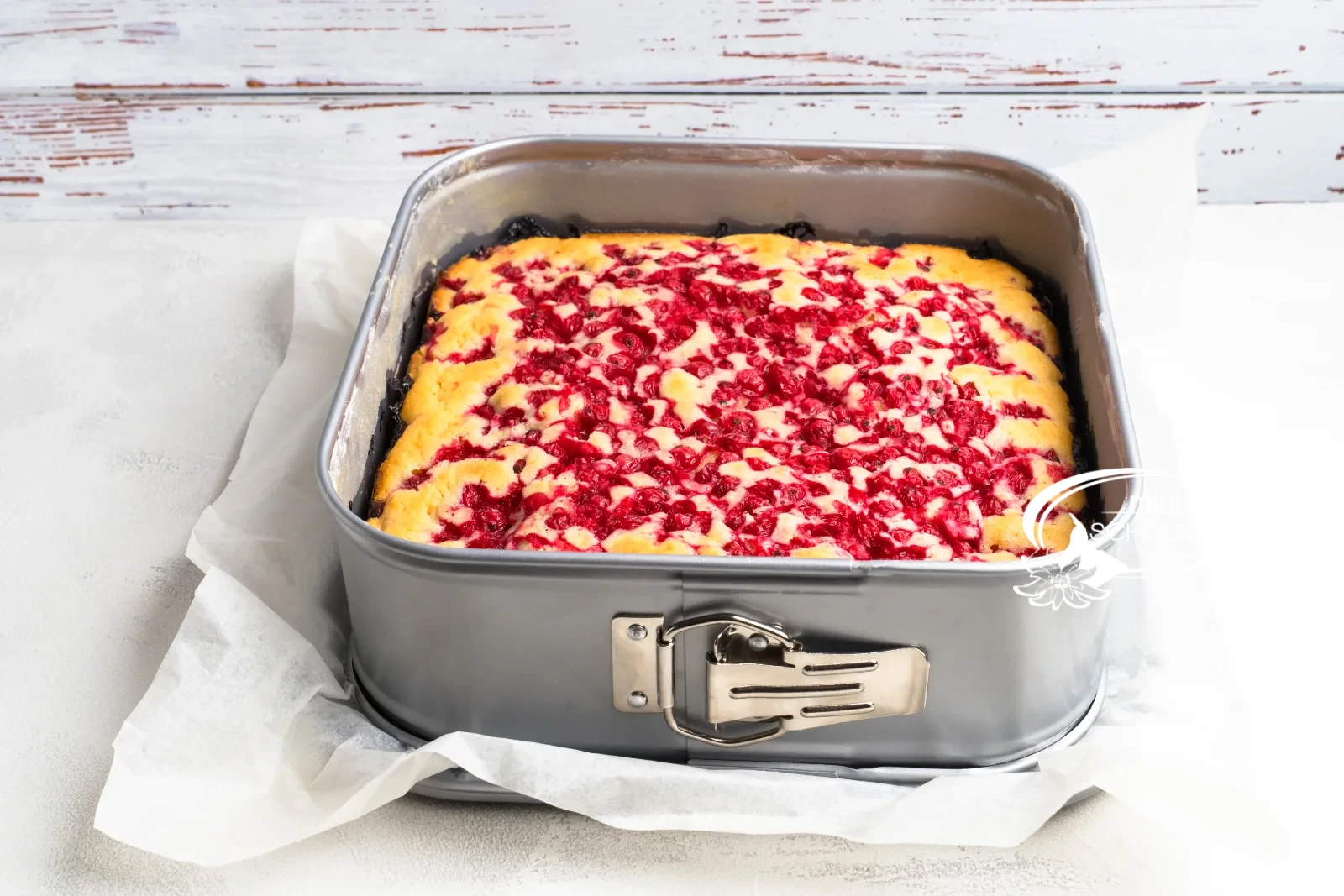 Stück Johannisbeerkuchen von oben auf dunklem Teller, umgeben von frischen Johannisbeeren