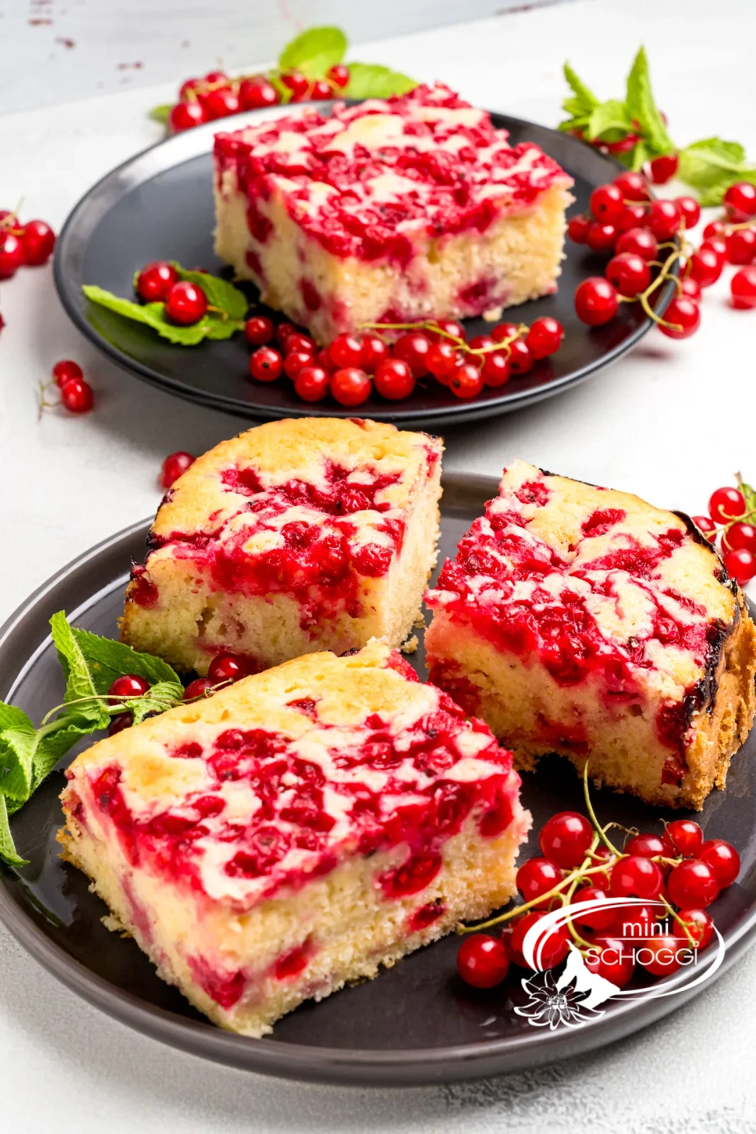 Stück Johannisbeerkuchen von oben auf dunklem Teller, umgeben von frischen Johannisbeeren