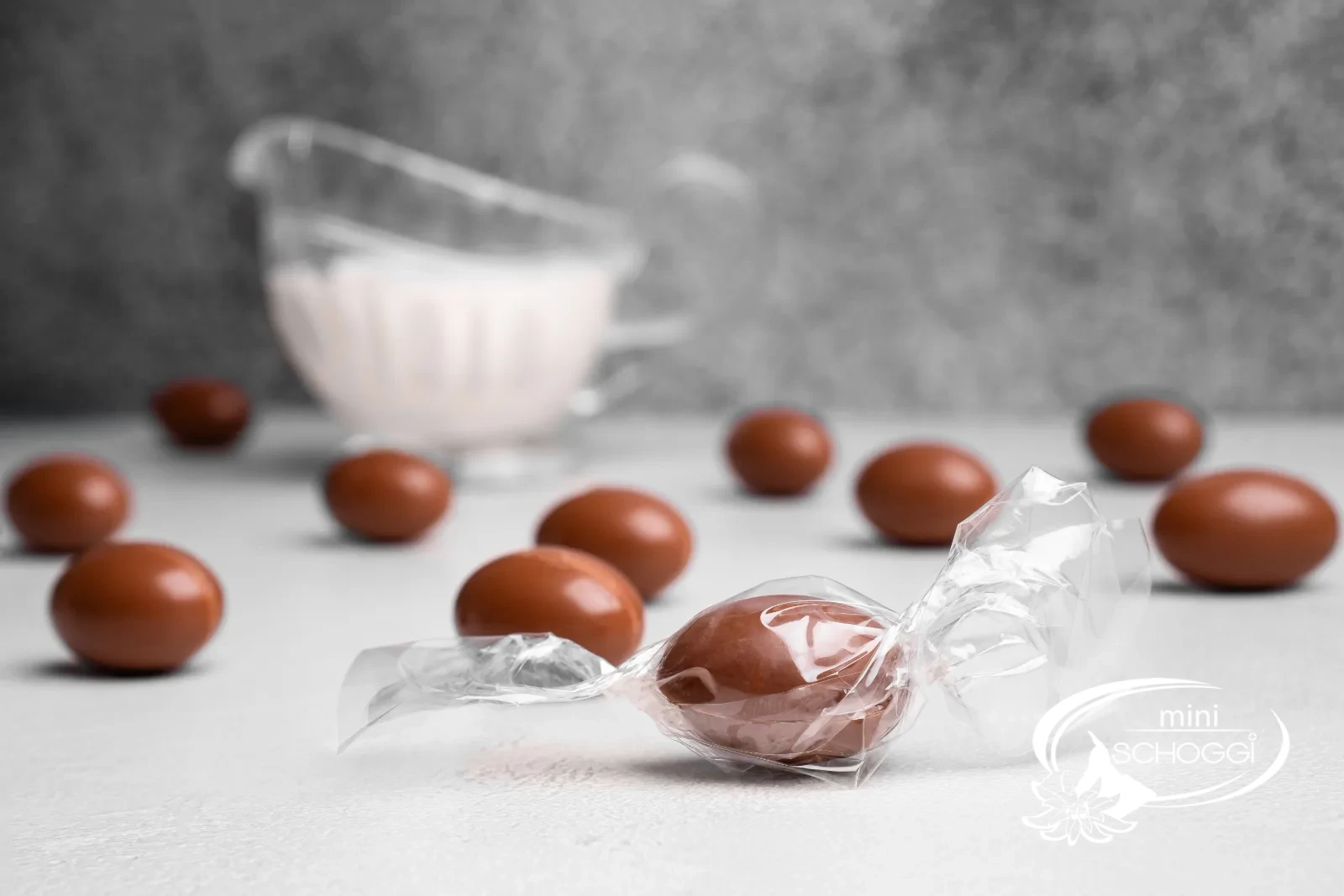 Un kinder schoko bons croqué révèle la ganache claire à la noisette, derrière le coquetier avec de petits œufs colorés