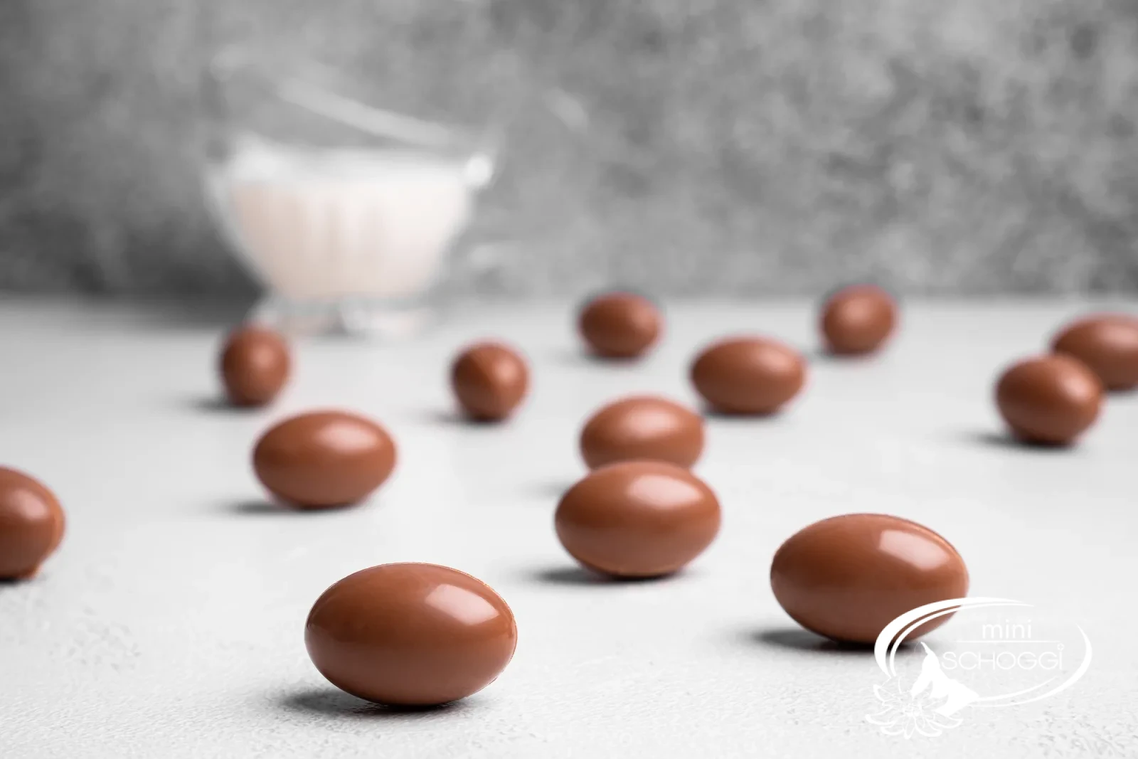 Un schoko-bon croqué révèle la Ganache claire à la noisette, derrière le coquetier avec des petits œufs colorés