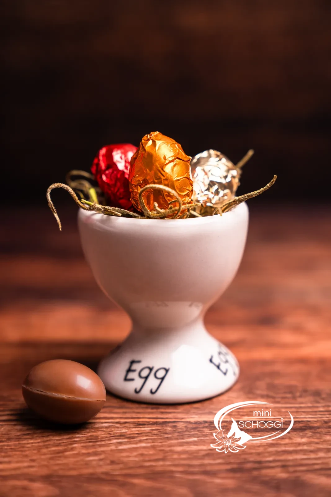 Un kinder schoko bons croqué révèle la ganache claire à la noisette, derrière le coquetier avec de petits œufs colorés