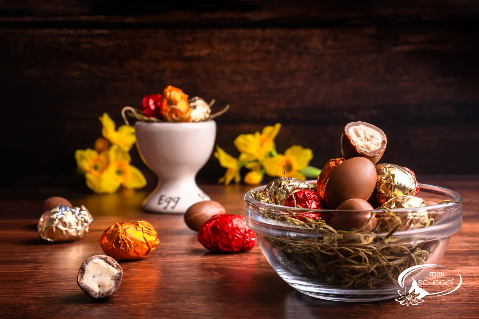 Un kinder schoko bons croqué révèle la ganache claire à la noisette, derrière le coquetier avec de petits œufs colorés