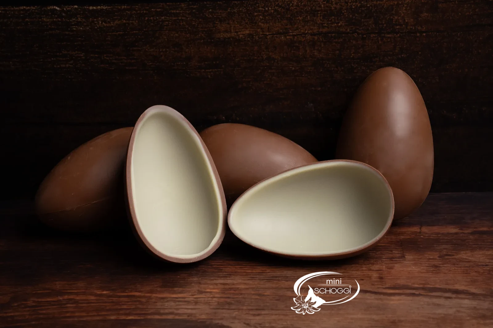 Opened chocolate egg with a white inner layer, next to whole surprise eggs
