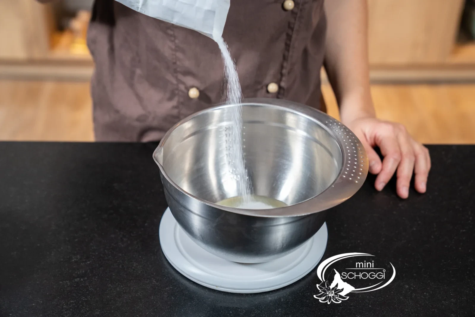 Zucker-Eiweiss-Masse mit Gelatine wird in einer Schüssel über dem Wasserbad gerührt, daneben ein digitales Thermometer