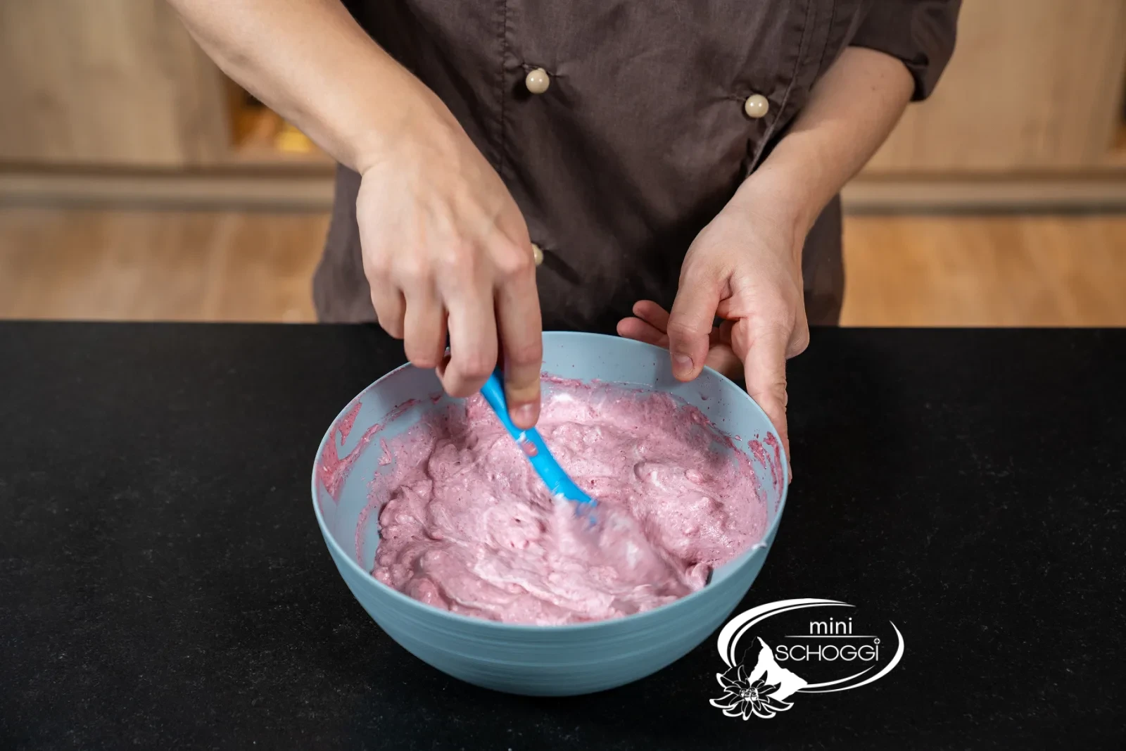 Rosa Mousse wird mit dem Spritzsack in die Mulden einer Silikonform in Kirschenform gefüllt
