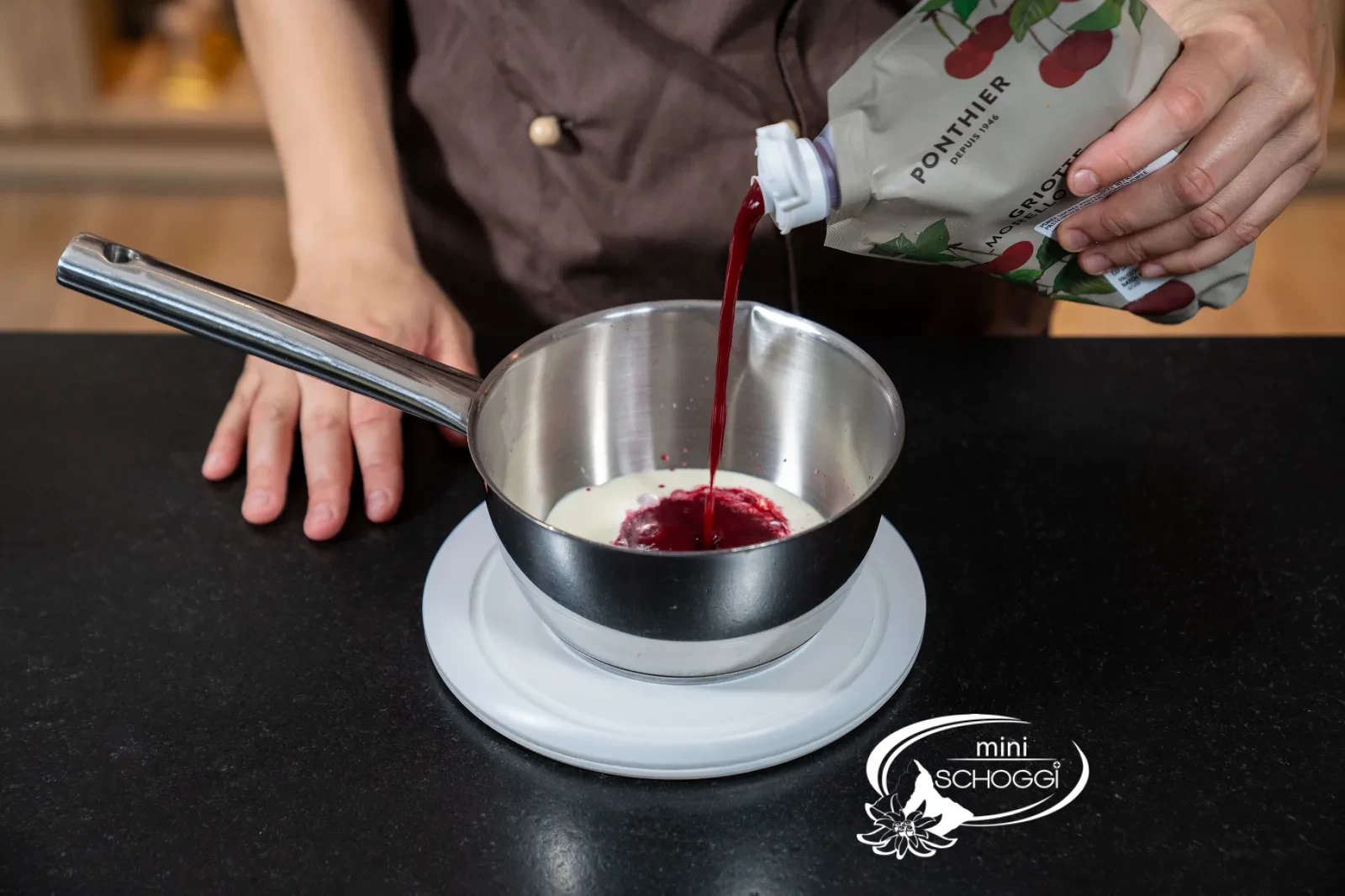 Rote Flüssigkeit aus Rahm, Sauerkirschpüree, Zucker und Glukose kocht in einer Pfanne auf