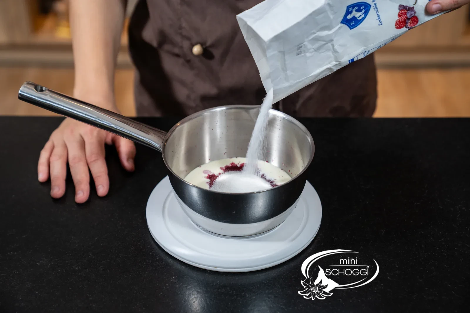 Rote Flüssigkeit aus Rahm, Sauerkirschpüree, Zucker und Glukose kocht in einer Pfanne auf