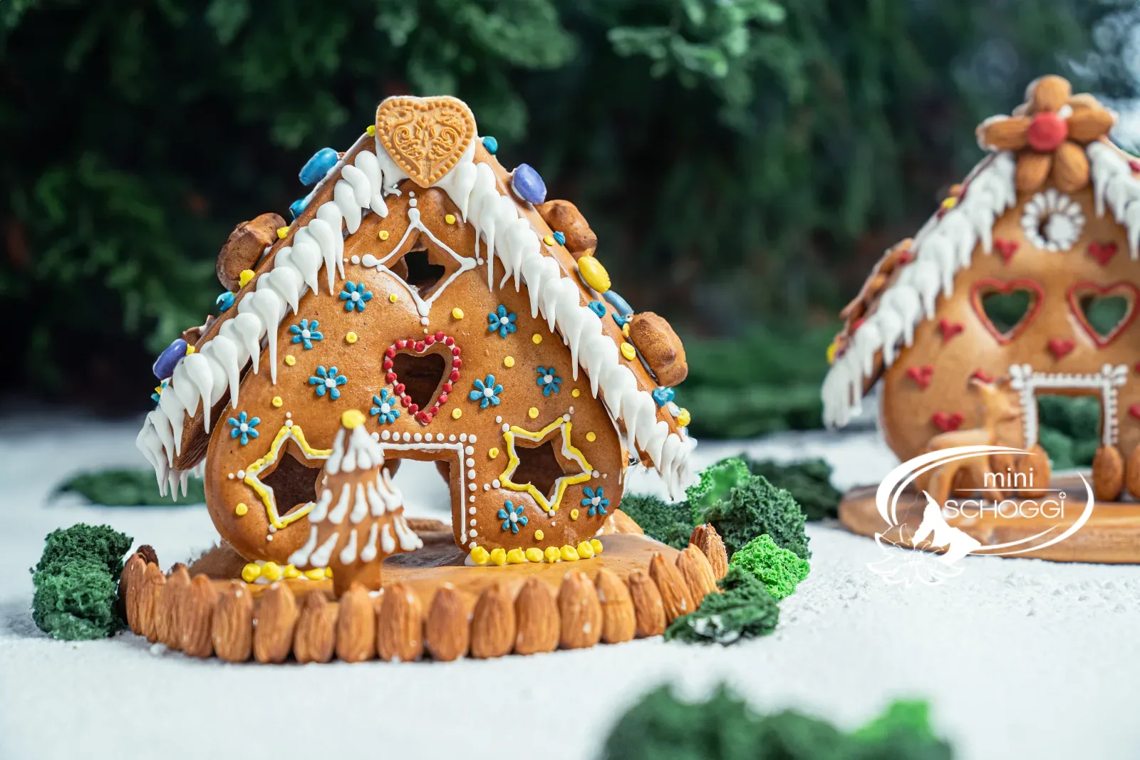 Casa di pan di zenzero finita e decorata con bordo di neve e tetto di mandorle