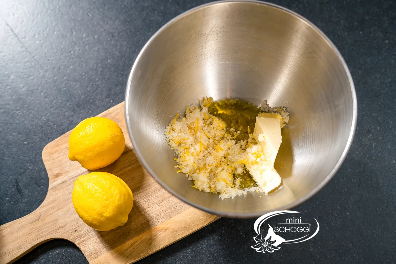Zitronenzucker in der Schüssel neben der Rührschüssel mit Butter und Olivenöl