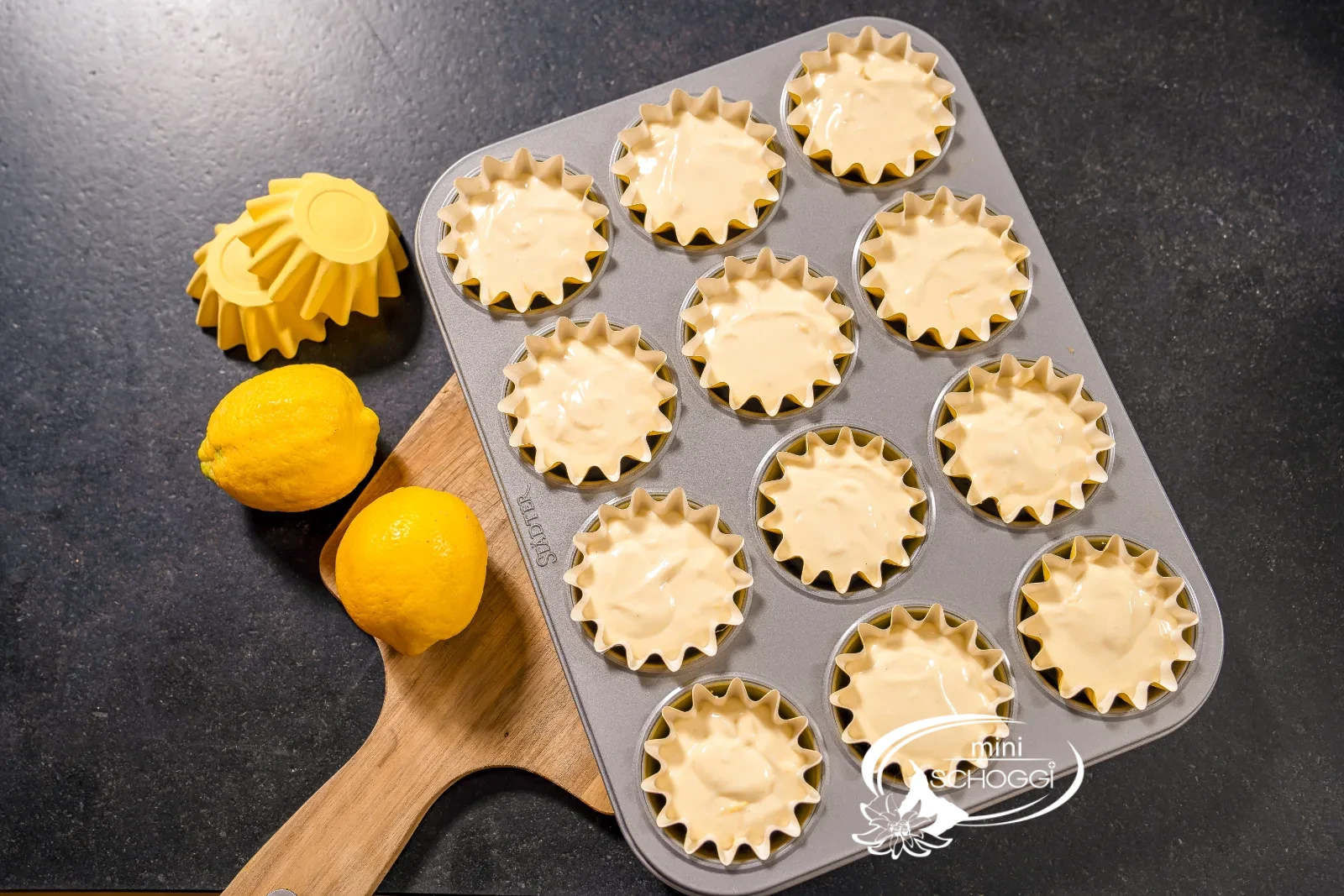 Cupcake-Teig wird mit dem Löffel aus der Schüssel portioniert