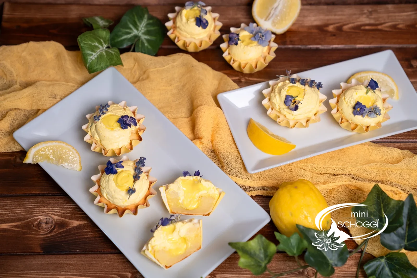 Lemon Cupcakes mit Zitronencreme und essbaren Blüten auf einer weissen Platte