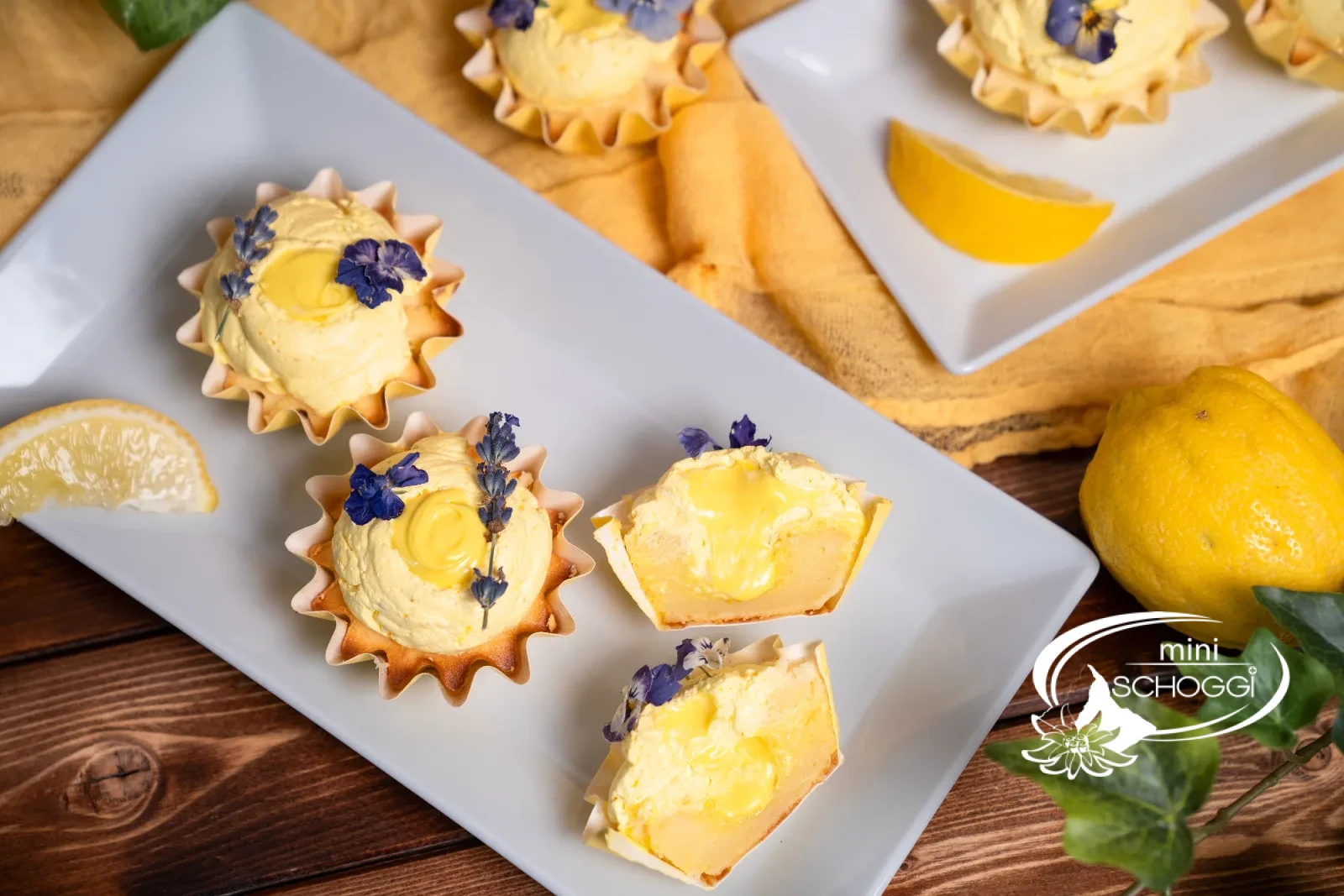 Fertige Lemon Cupcakes mit ganzer Zitrone auf gelbem Tuch