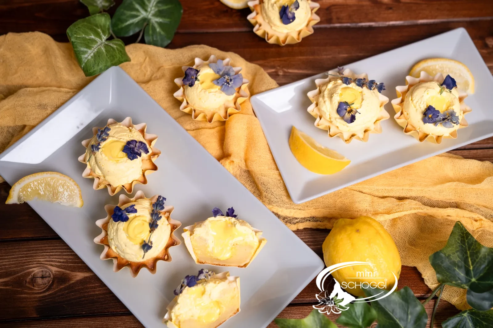 Fertige Lemon Cupcakes mit Frosting und essbaren Blüten auf der Servierplatte
