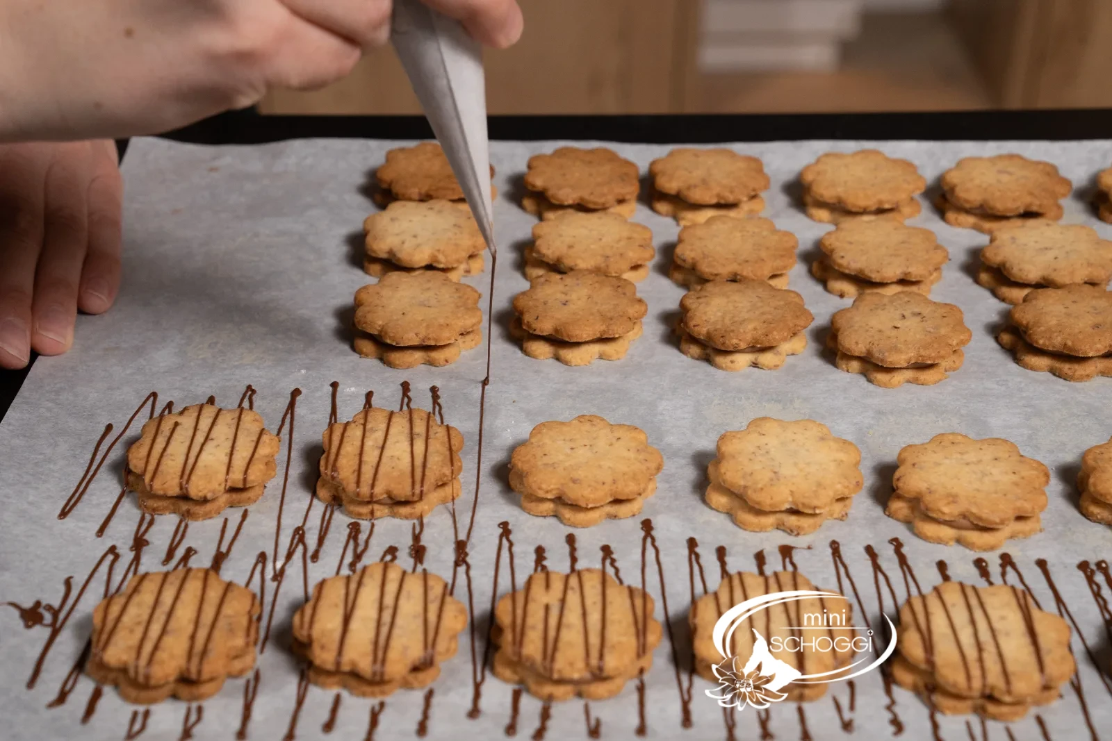 Con il cornetto di carta si tracciano sottili linee di cioccolato sui biscotti