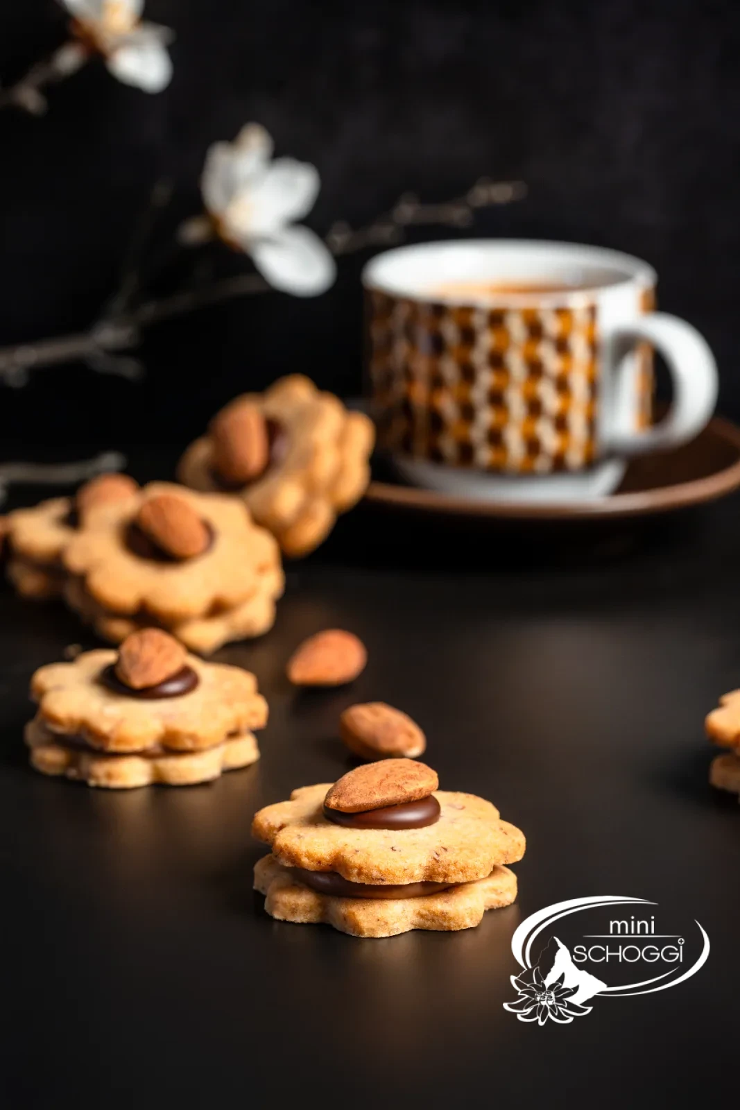 Biscotti con le mandorle impilati con ripieno di Gianduja davanti a una tazza di caffè