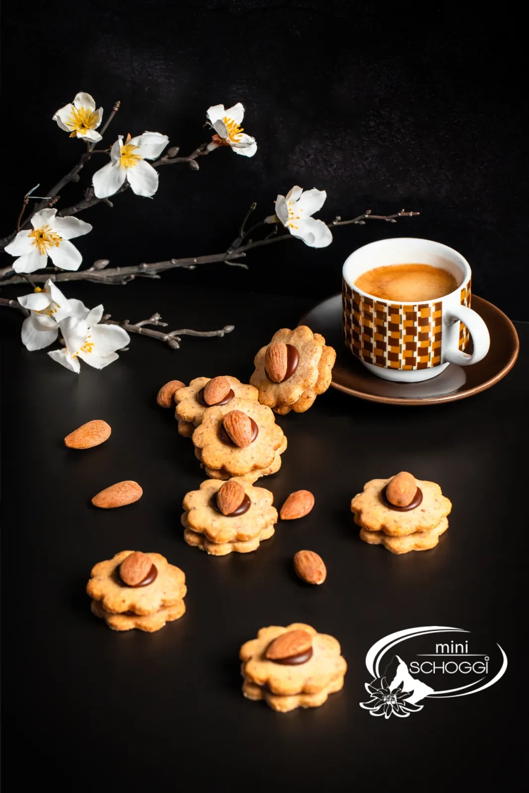 Biscotti con le mandorle impilati con ripieno di Gianduja davanti a una tazza di caffè