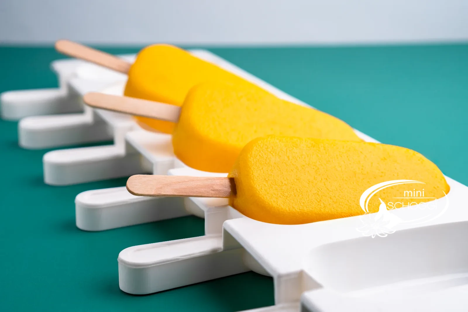 Gelato al mango e yogurt su stecco in primo piano su sfondo verde