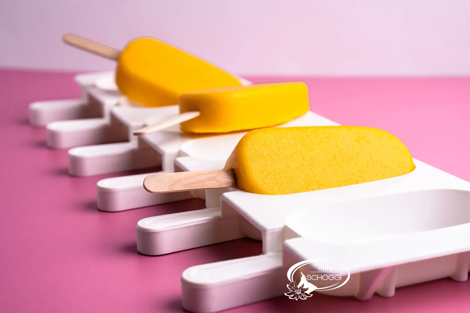 Gelato al mango e yogurt su stecco nello stampo per gelato bianco su sfondo rosa