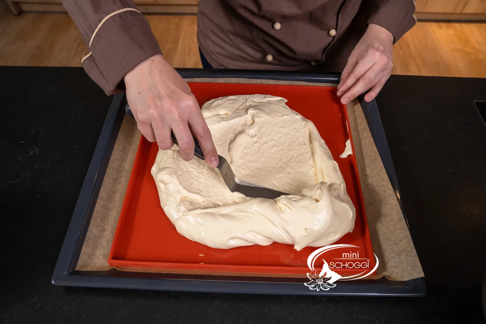 La massa del pan di Spagna viene versata sul tappetino per rotolo rosso in silicone