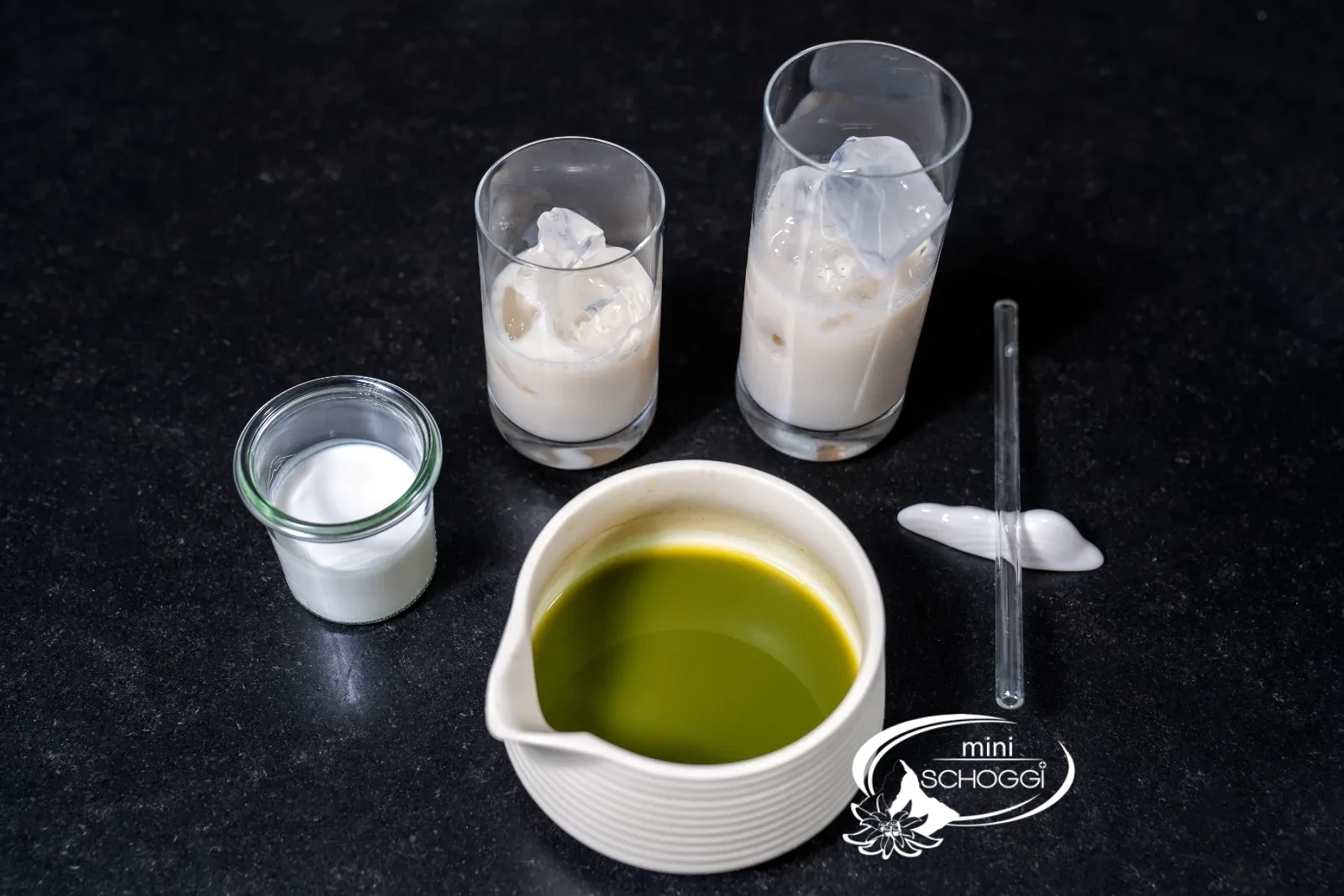 Ice cubes and milk in two glasses next to the matcha bowl