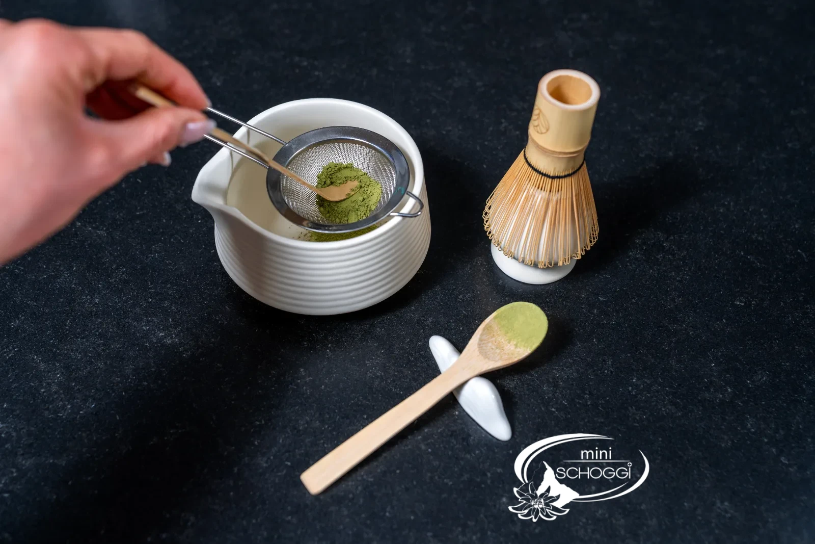 Matcha powder in the sieve over the white bowl