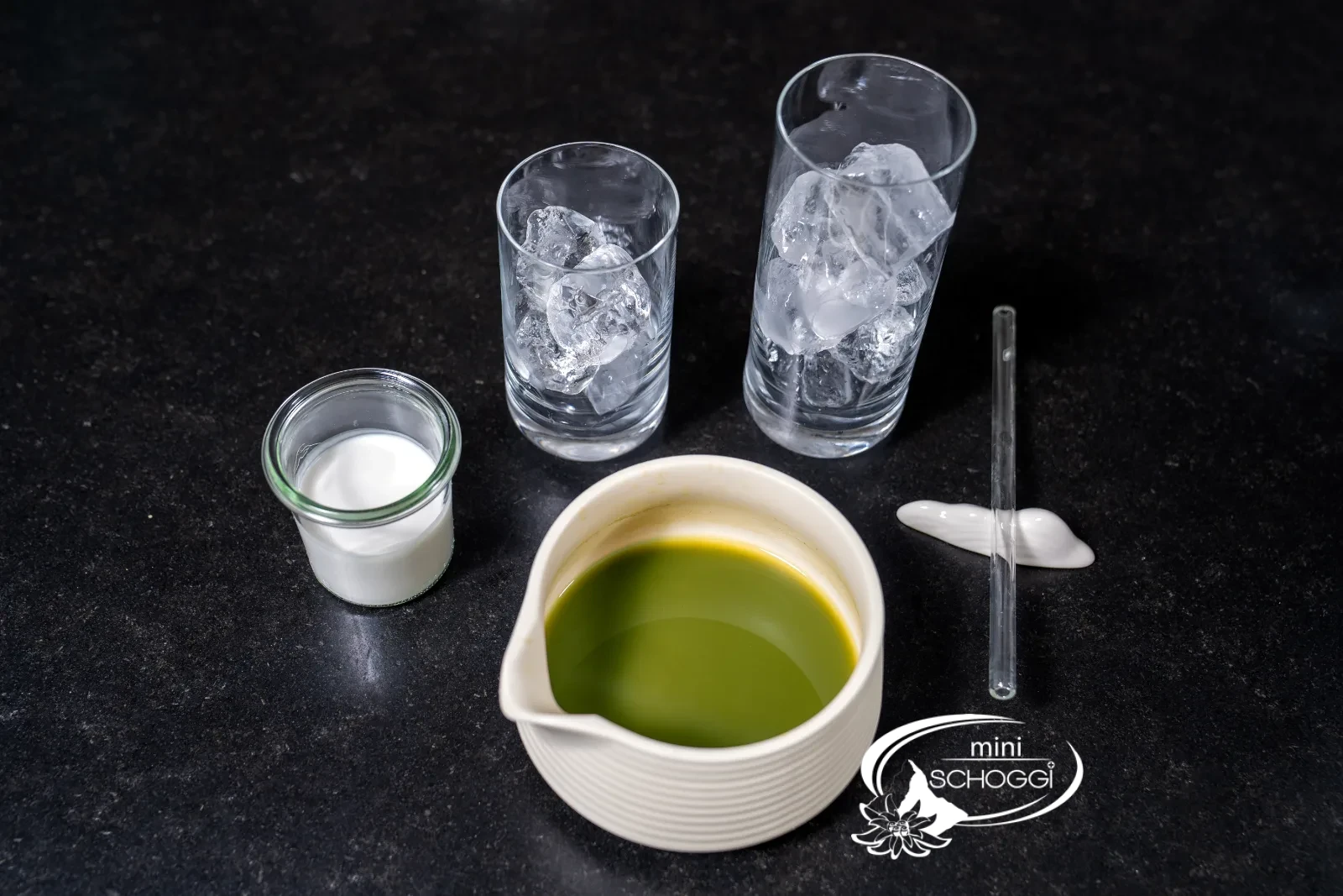 Glasses with ice cubes, a glass of milk and the bowl of matcha ready