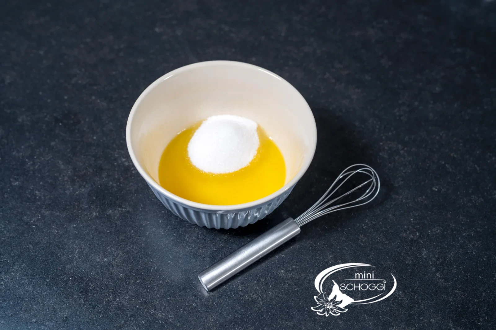 Geschmolzene Butter mit Zucker in der Schüssel, daneben der Schwingbesen