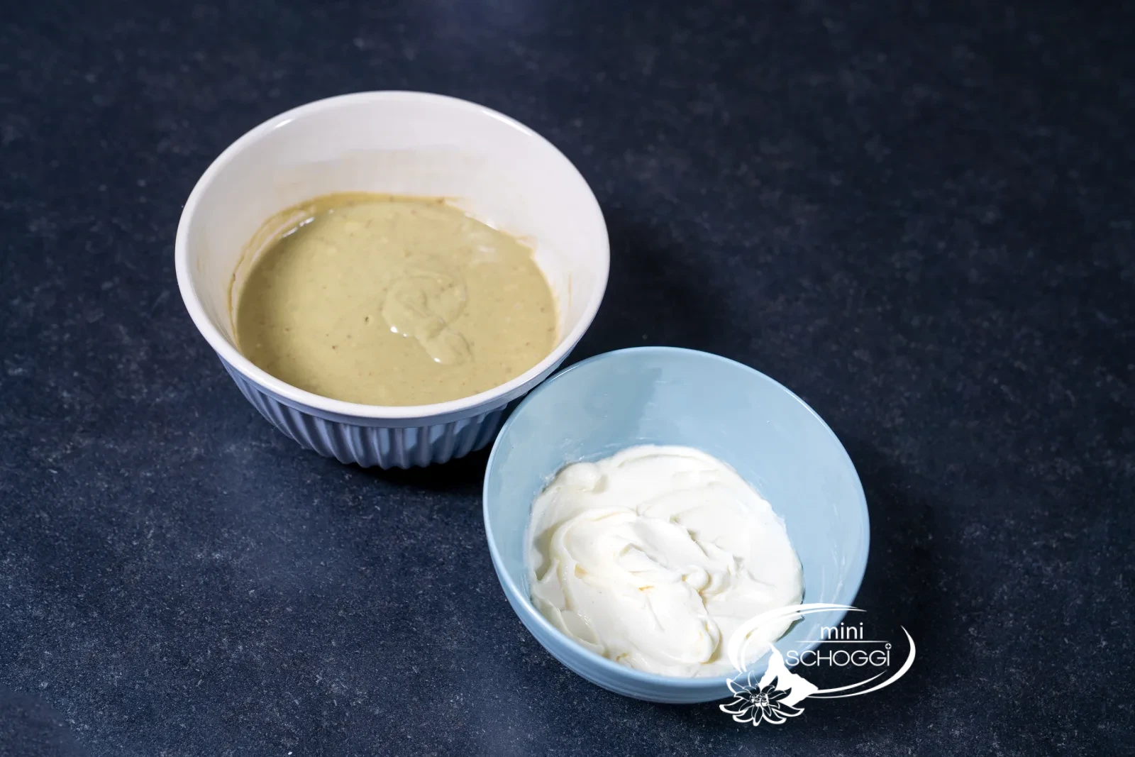 Glatt gerührte Frischkäsecreme neben dem Matcha-Teig