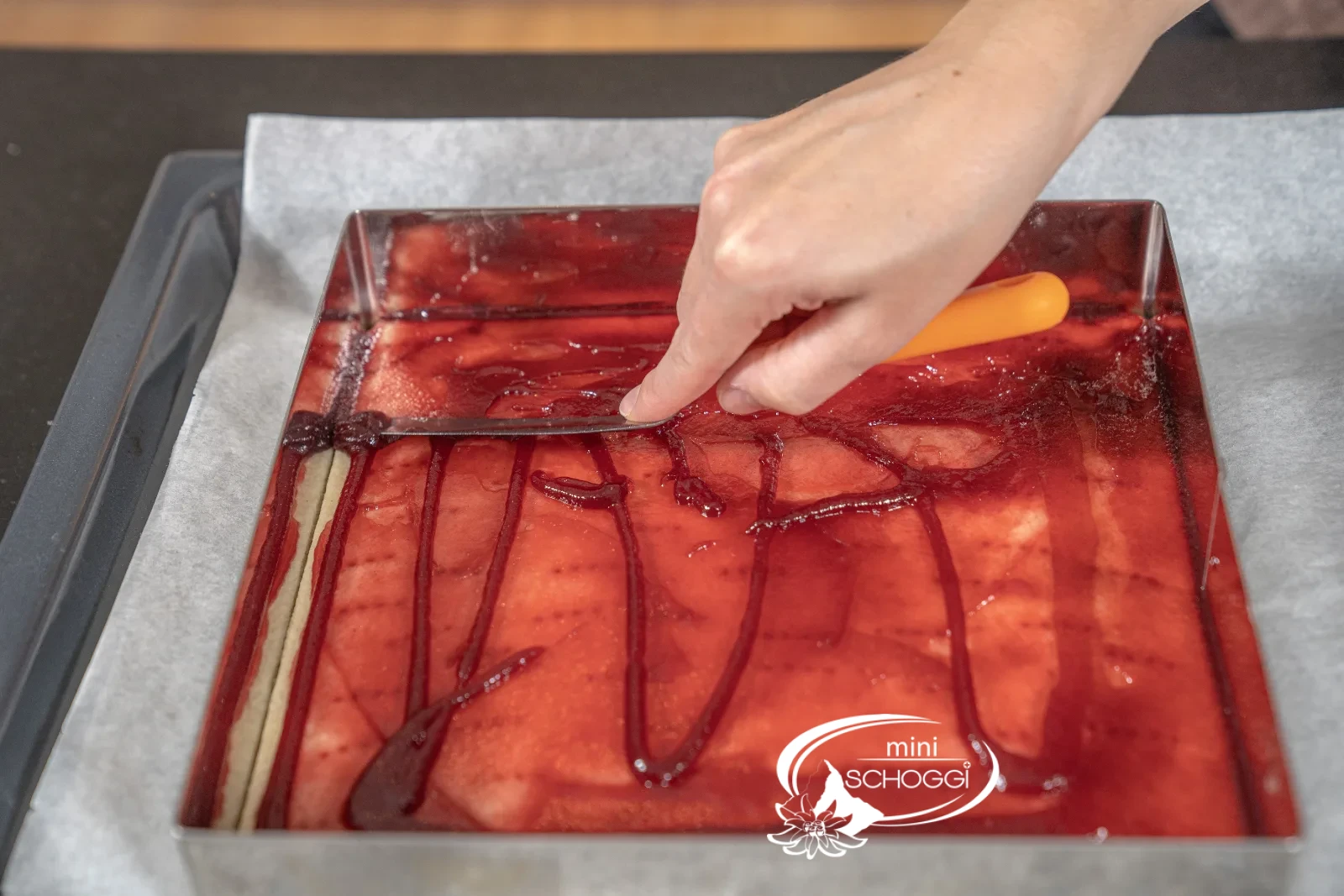 La confiture de framboise est étalée sur le fond avec la spatule coudée