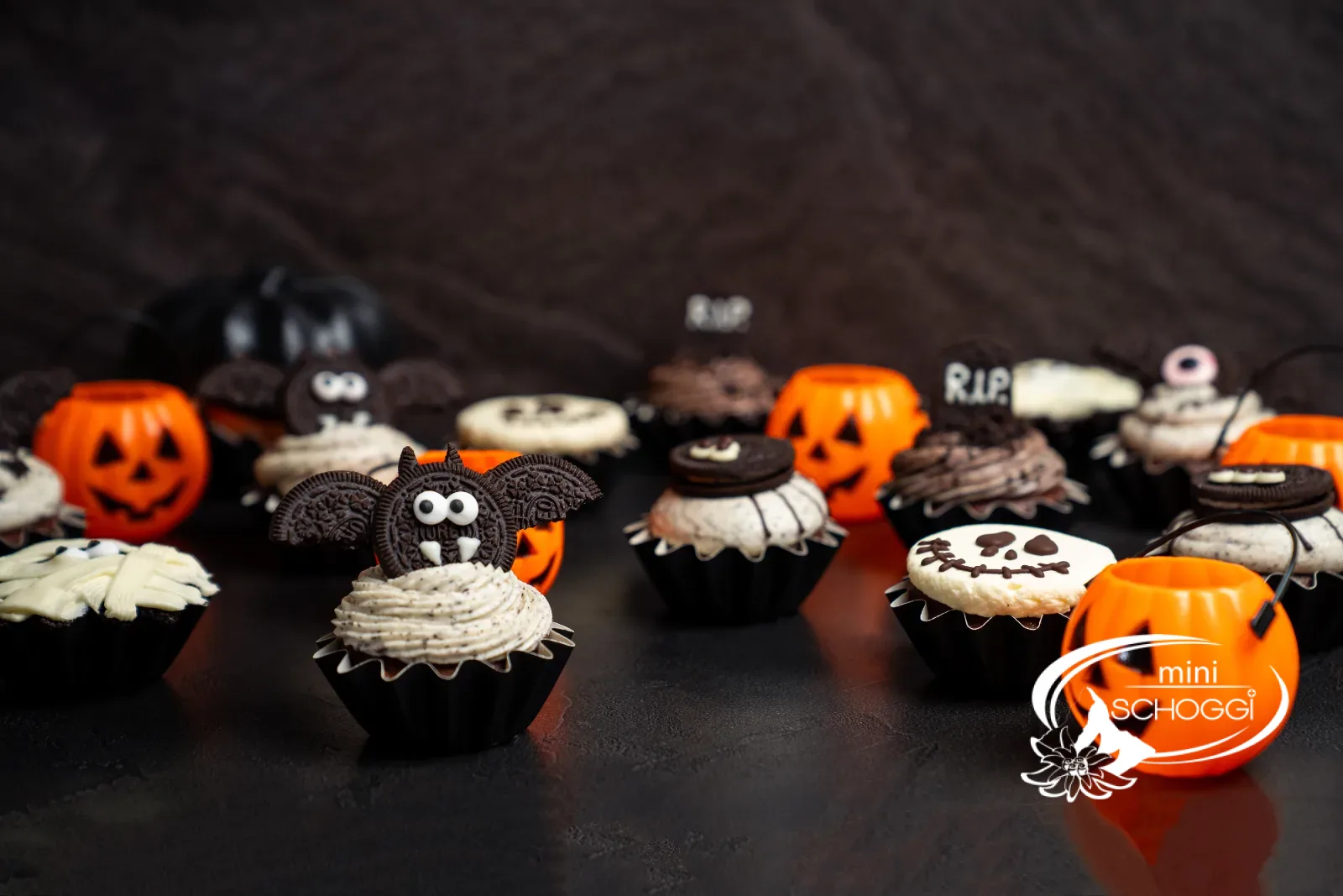 Reihe von Halloween-Cupcakes mit Kürbissen auf dunklem Tisch