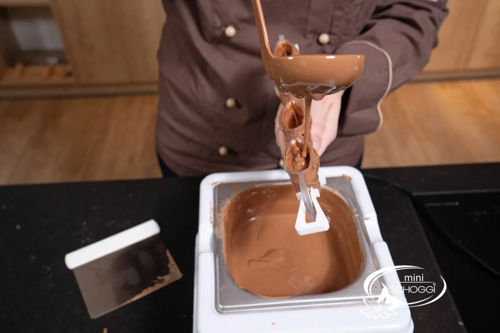 I bordi dello stampo vengono liberati dalla copertura di cioccolato in eccesso con la Spatola
