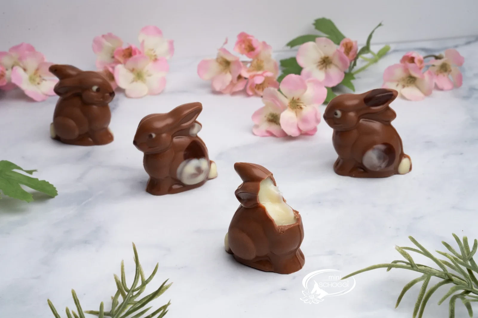 Conigli di cioccolato tra delicati fiori primaverili