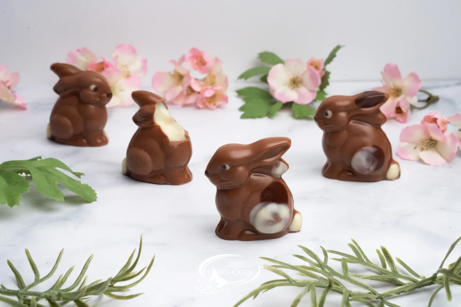 Conigli di cioccolato tra delicati fiori primaverili