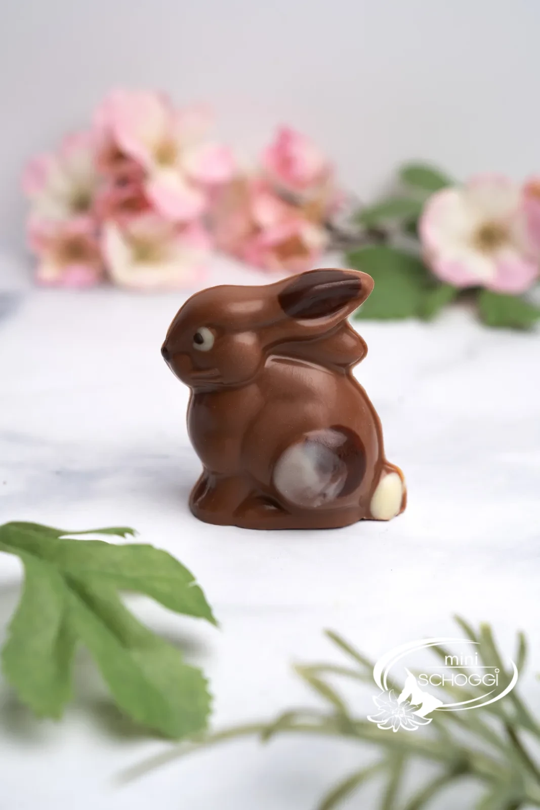Conigli di cioccolato tra delicati fiori primaverili