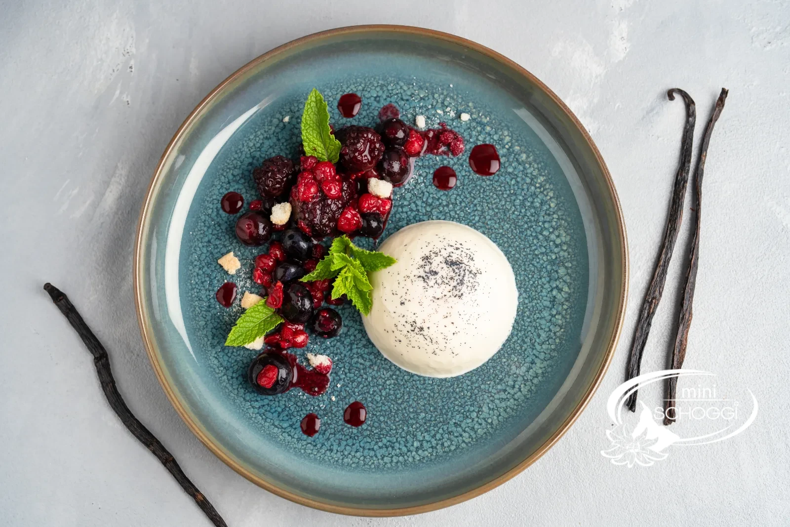 Panna cotta démoulée avec fruits rouges et menthe sur une assiette bleue
